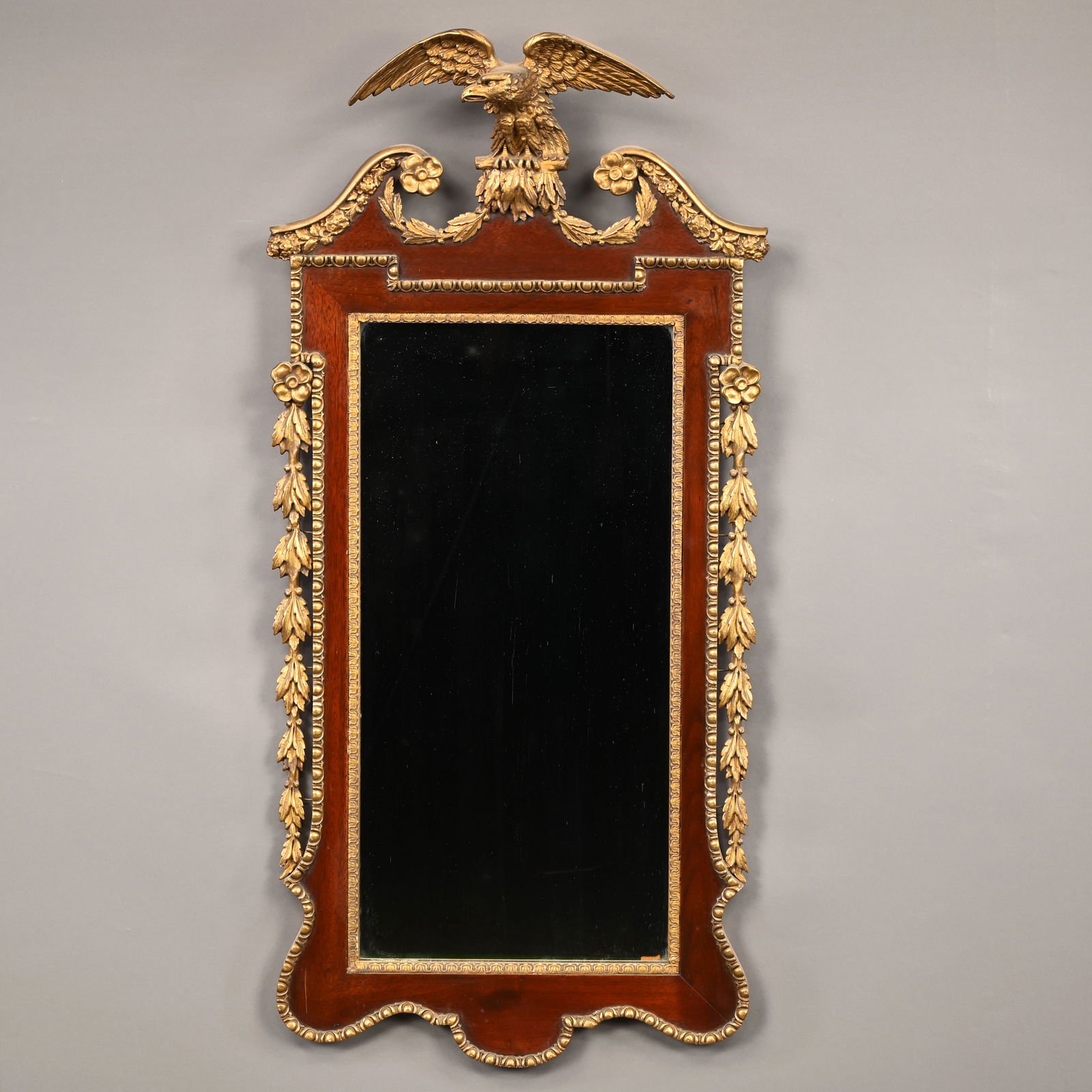 Chippendale Style Mahogany and Parcel-Gilt Mirror: Chippendale Style Mahogany and Parcel-Gilt Mirror. The rectangular mirror plate within a molded gilt foliate surround, the rectangular upper corners and serpentine apron outline with gilt egg-and-dart