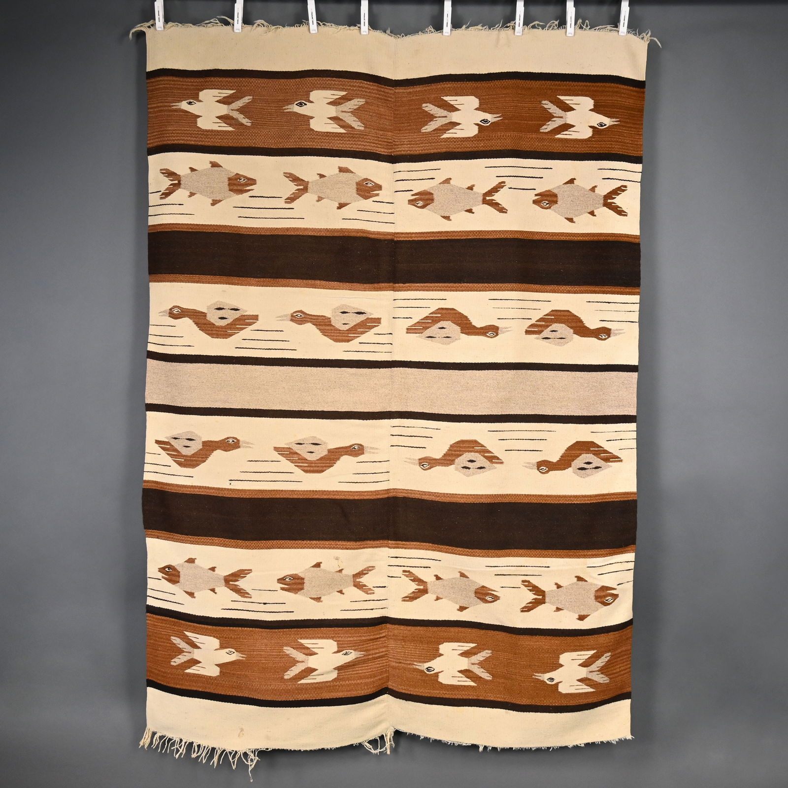 Zapotec Woven Wool Bird, Fish and Duck Rug: Zapotec Woven Wool Bird, Fish and Duck Rug. Woven in brown, black and ivory yarns with alternating rows of four fish, four birds in flight and four ducks, two fringed ends.52.5 in. x 75.125 in.