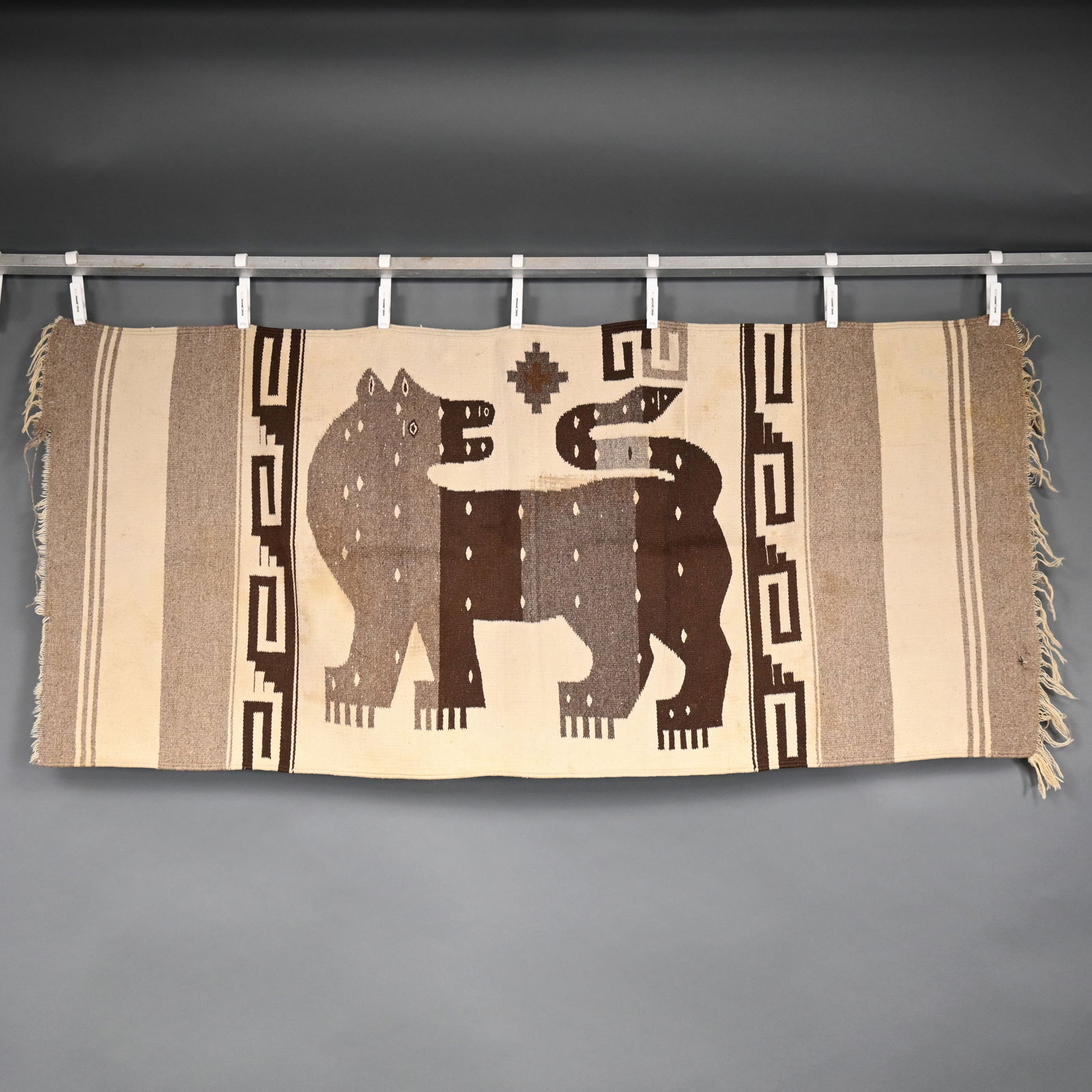 Southwest Wool Weaving of a Lion: Southwest Wool Weaving of a Lion, 20th Century. Woven in ivory, grey and shades of brown yarns with a depiction of a lion looking over his shoulder, within step-fret borders and fringed ends.29.5 in.