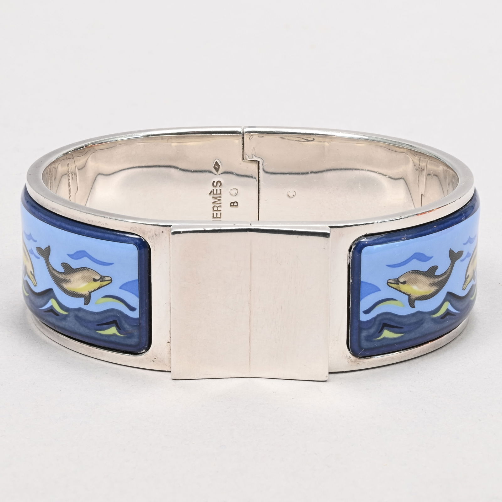Hermes Enamel and Silver Clic Clac Bracelet: Hermes Printed Enamel and Silver Clic Clac Bracelet. Depicting dolphins, marked "HERMES" B, asterisks in lozenge, minerva head.Diam: 5 in.Band W: 0.78 in.