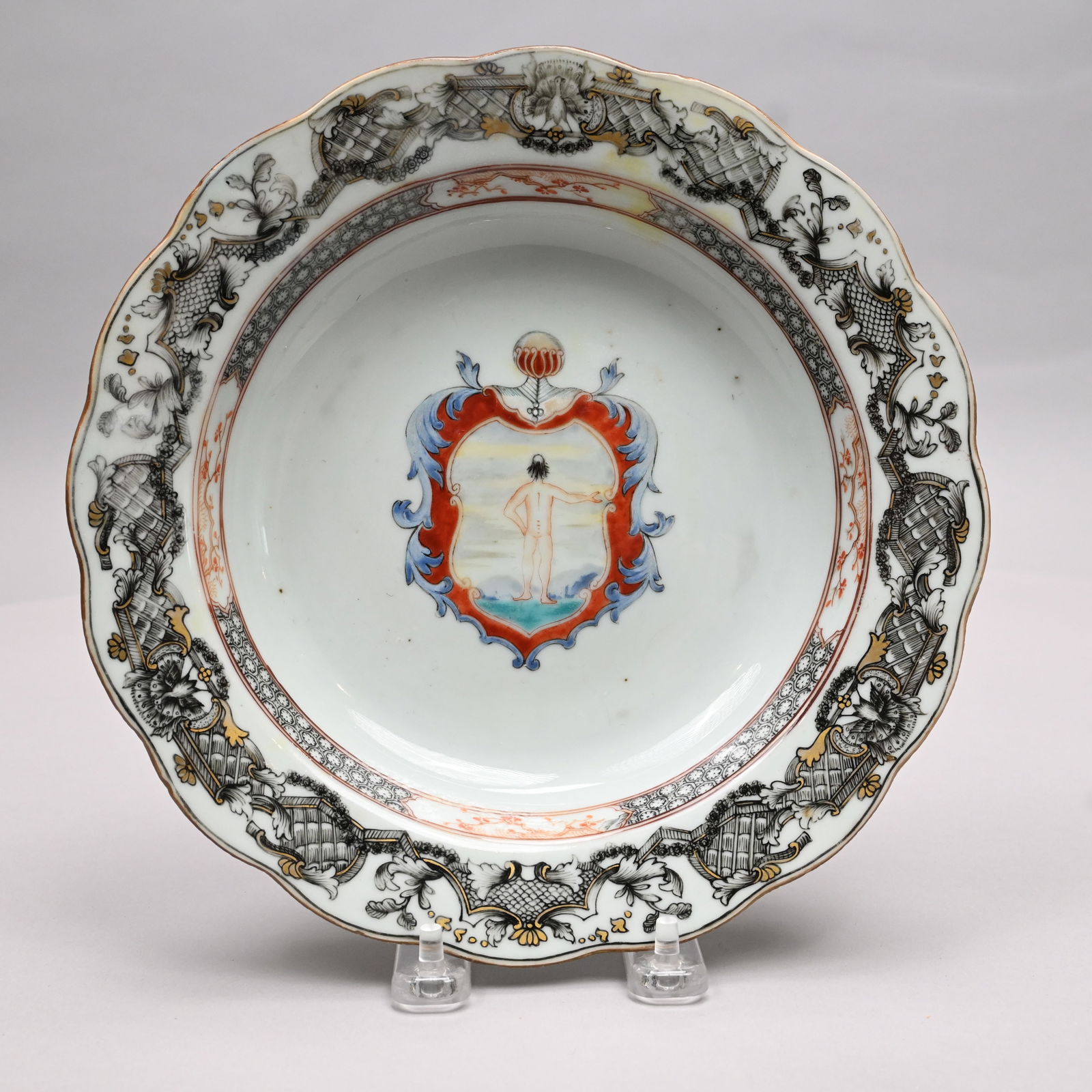 Chinese Export Porcelain Armorial Soup Plate: Chinese Export Porcelain Armorial Soup Plate, Circa 1750. Painted in iron-red, blue, turquoise and black enamels with a shield enclosing the view of a nude boy from the back with one arm