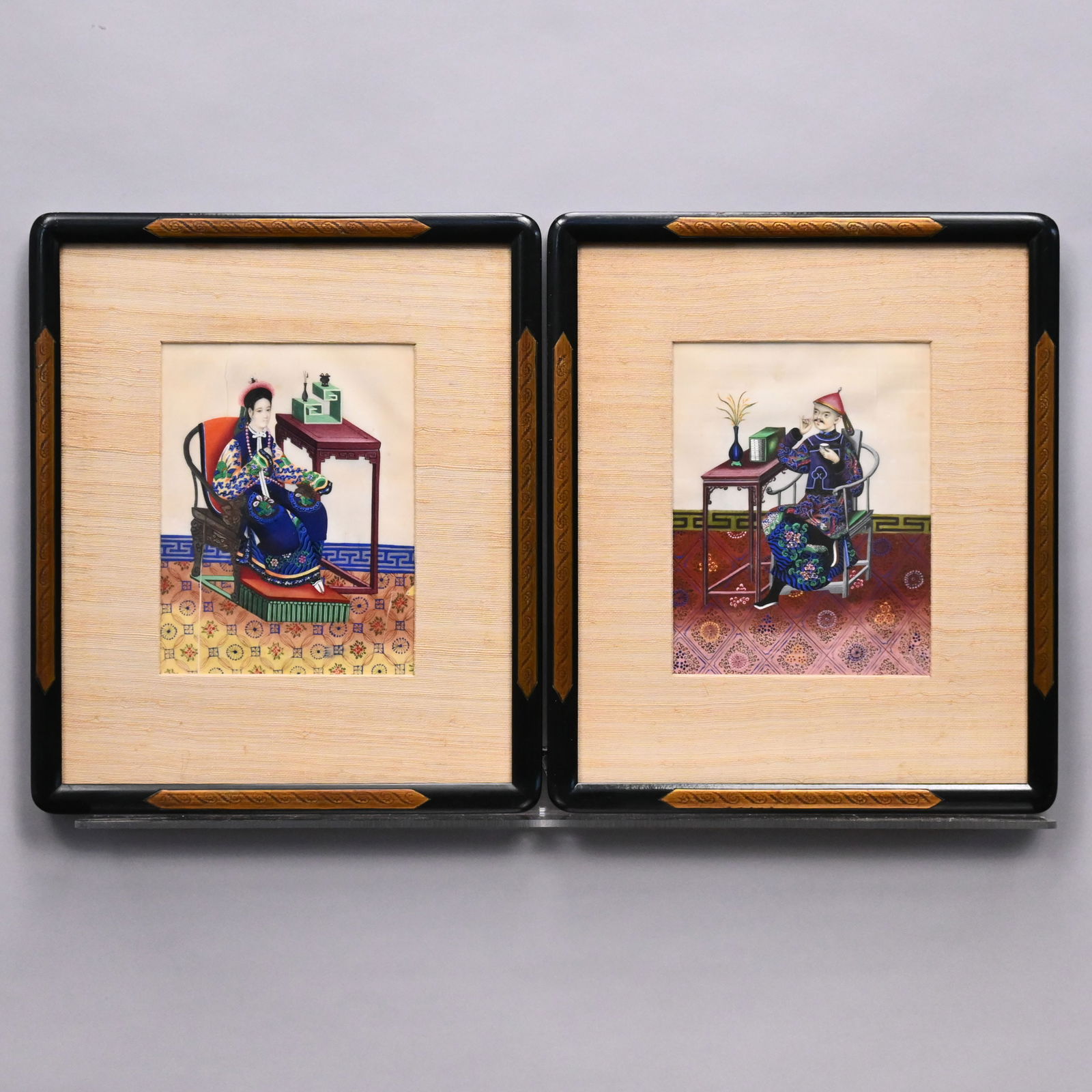 Pair of China Trade Watercolors: Pair of China Trade Watercolors of a Chinese Man and Woman. Depicted seated in an interior with tables and ornate carpets. Each watercolor on pith paper, (8.5 x 6.5 inches, sight). Framed in grass