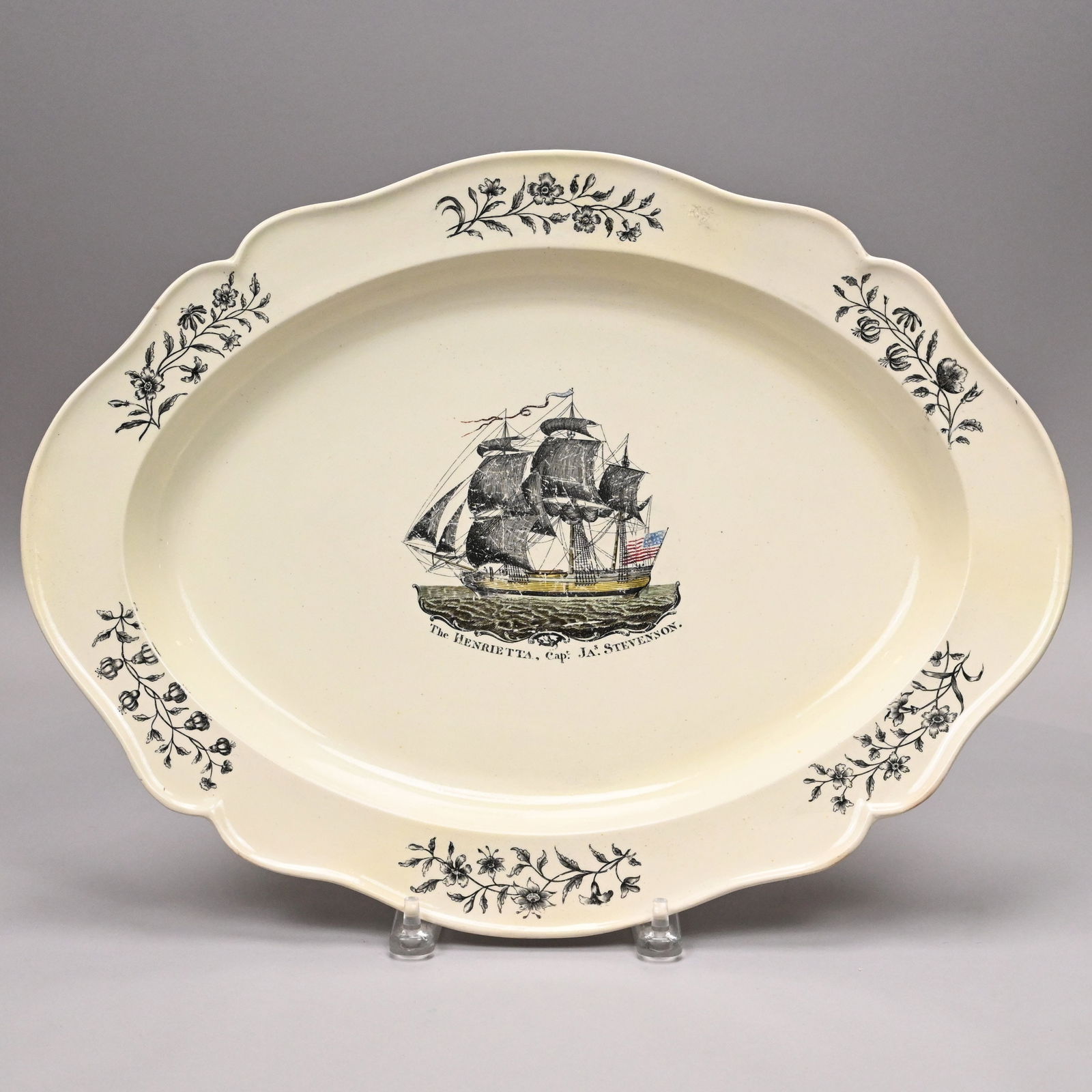 'The Henrietta,' English Creamware Platter: 'The Henrietta, Cap.t Jas. Stevenson,' English Creamware Black Transfer-Printed and Enamel-Decorated Platter, Circa 1800. Printed with a view of the three-masted American ship above the inscription