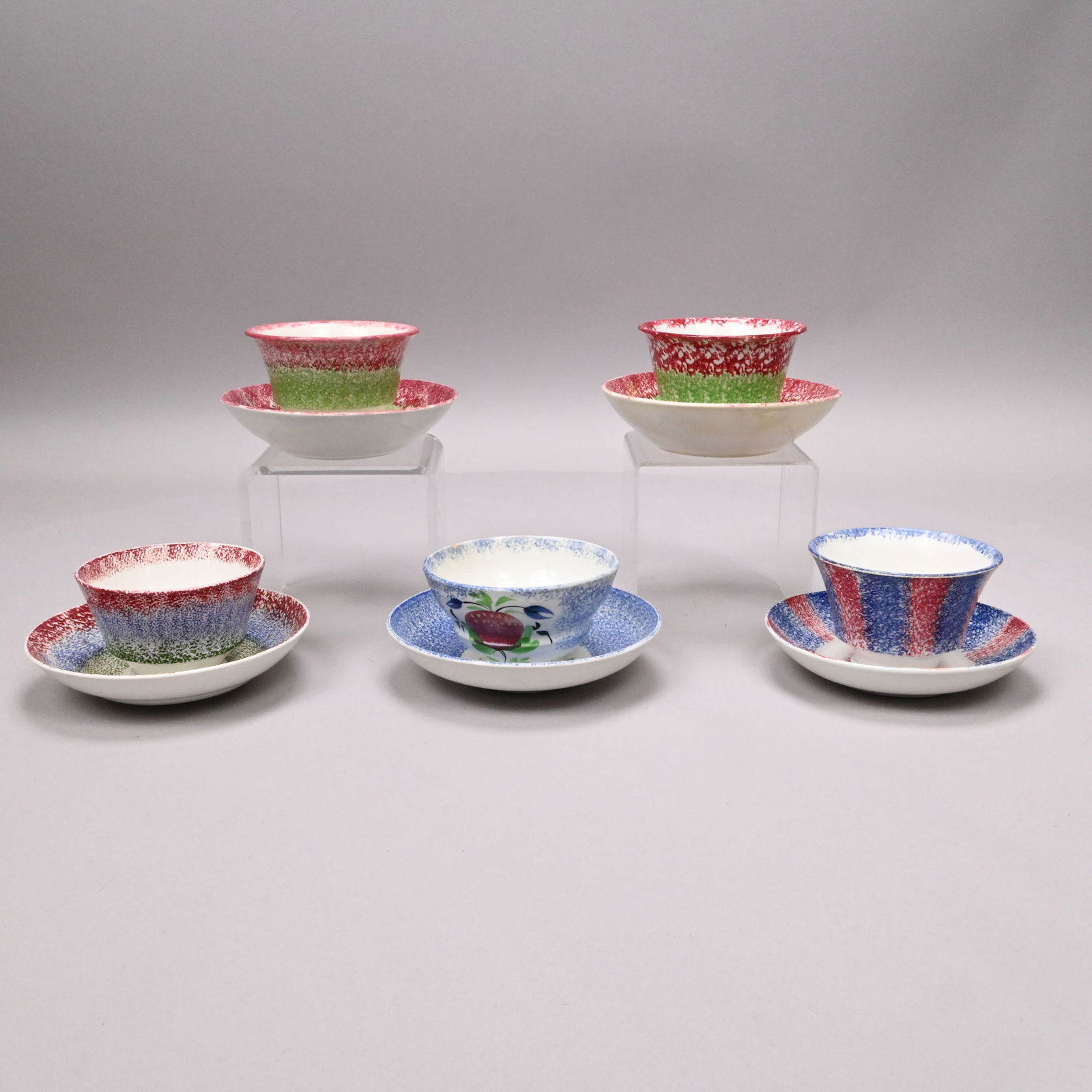 Five British Spatterware Handleless Cups & Saucers: Five British Spatterware Handleless Cups and Saucers, Mid-19th Century. Comprising a rainbow set sponged with red, blue and green bands, the saucer impressed "ADAMS;" a rainbow set sponged with red
