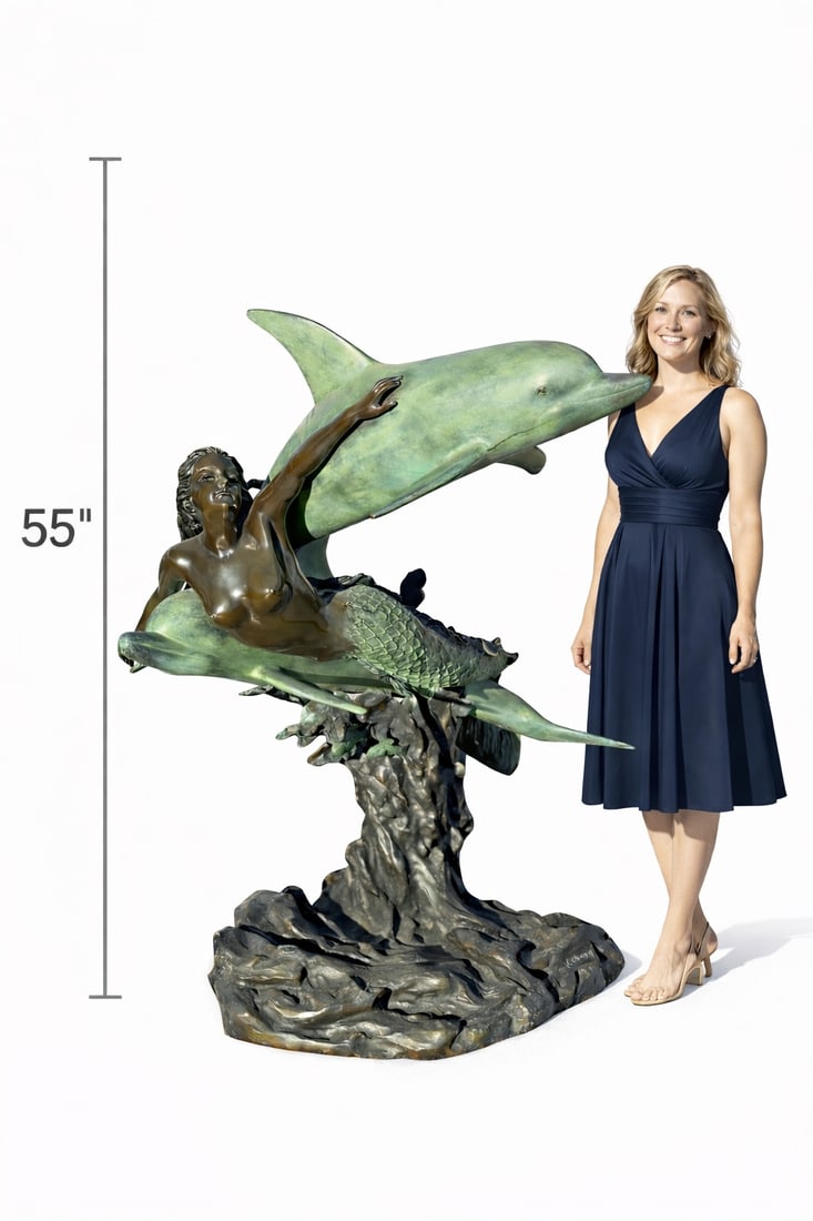 Near life-size bronze mermaid Fountain Sculpture: Size: 55 in x 58 in This sculpture features a graceful mermaid riding alongside two dolphins, captured in a dynamic and flowing composition. The mermaid’s bronze-toned upper body contrasts