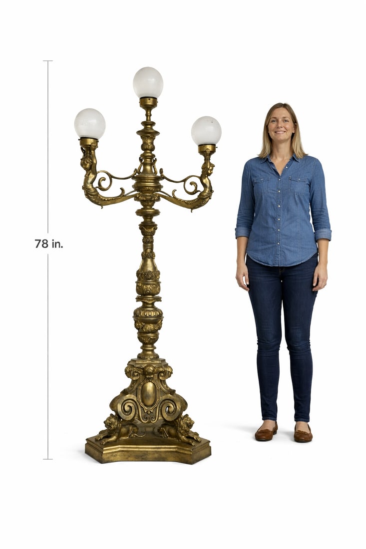Ornate Figural Brass Floor Lamp with Cherubs and Frosted Glass Globes: This ornate antique-style floor lamp is crafted in richly patinated brass or bronze and features an elaborate figural design inspired by classical European decorative arts. The lamp is composed of