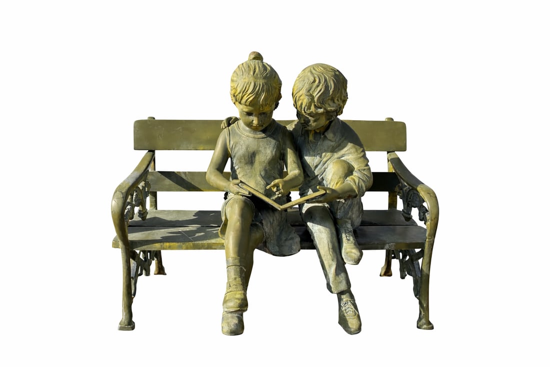 Life Size Bronze Bench Kids Sculpture by Jim Davidson: size 50 inches x 40 inches x 20 This charming sculpture depicts two children seated closely together on an ornate bench, sharing a quiet moment as they read a book. The figures are rendered with