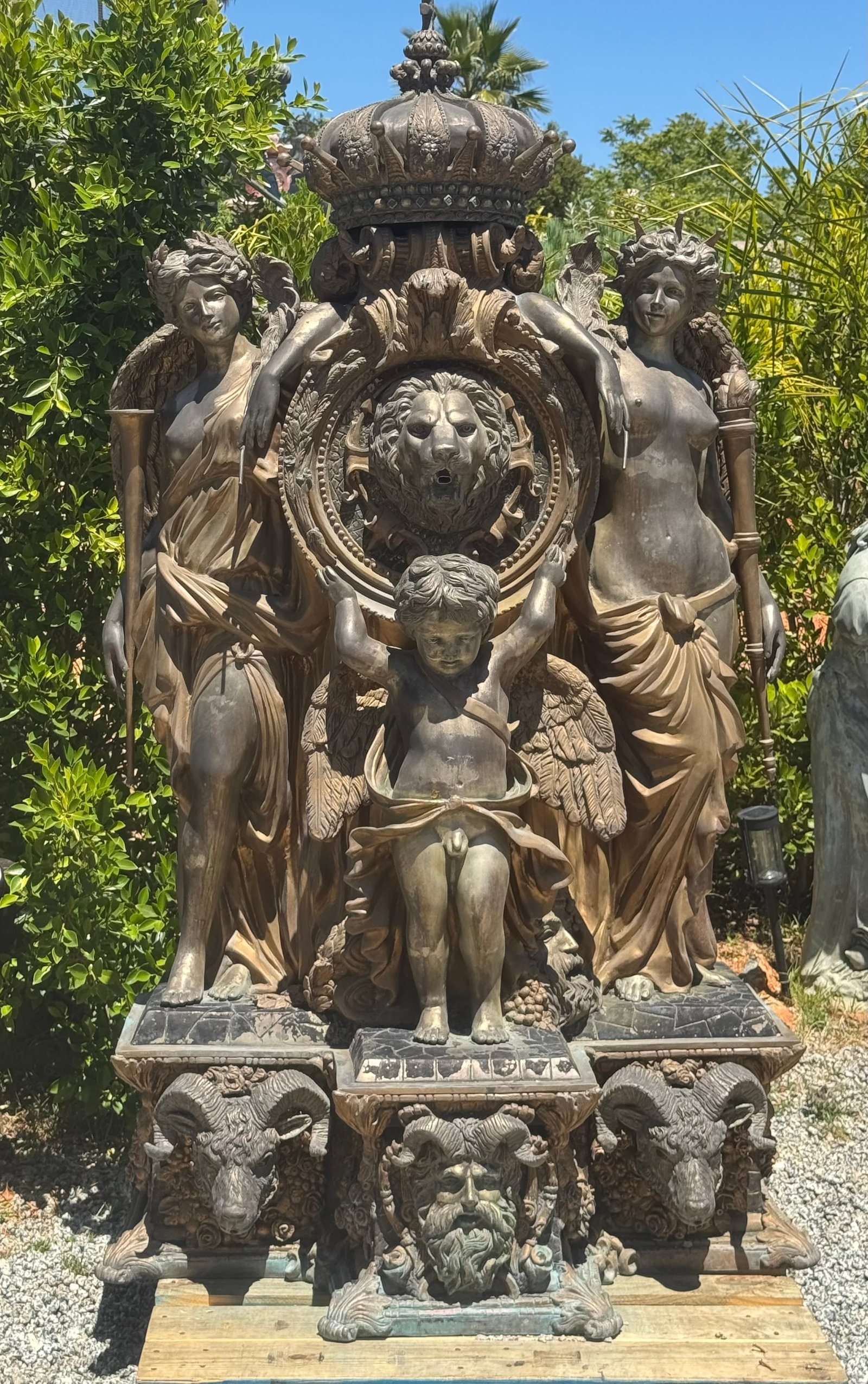 Monumental Classical Bronze-Style Fountain Sculpture with Crown, Lion, Cherubs & Female Figures: Size:84”H, 64”W,30”DMonumental classical fountain sculpture featuring female figures, cherub, lion head, royal crown, ram heads, and ornate European-style details. A dramatic stateme