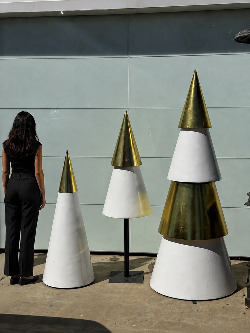 Modern White and Gold Cone Christmas Tree Sculptures - Set of 3: Size: tallest one 76 in H x 30 the middle one is 62 in x 18 in and the little one 50” x 25”. Modern decorative sculptures are made of white and gold-toned metal. The set includes three tie