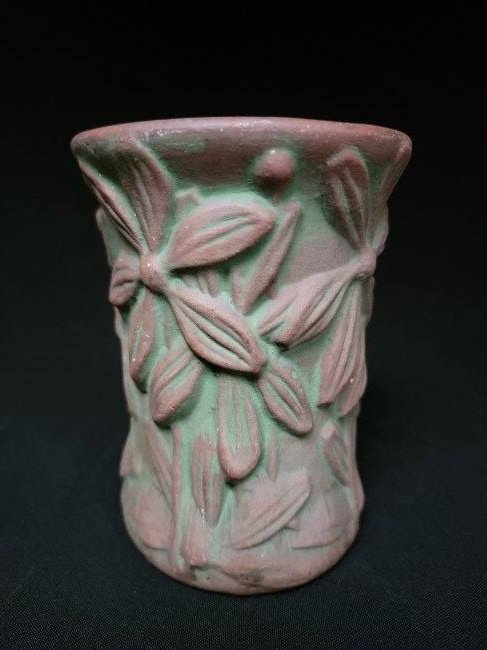 Peters & Reed "Moss Aztec" Daisy Vase C.1890: This vase depicts an embossed daisy style flowers on long stems. The piece is glazed in the Moss Aztec technique which is a terracotta with a Verde accent applied over it. It resembles moss that grows