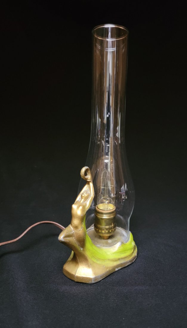 Art Deco Table Lamp: Antique Art Deco table lamp with a well poised woman painted in gold with her hair flowing a light green behind her. Lamp works! Cord is safe. Chimney on lamp is not original and predates the lamp by