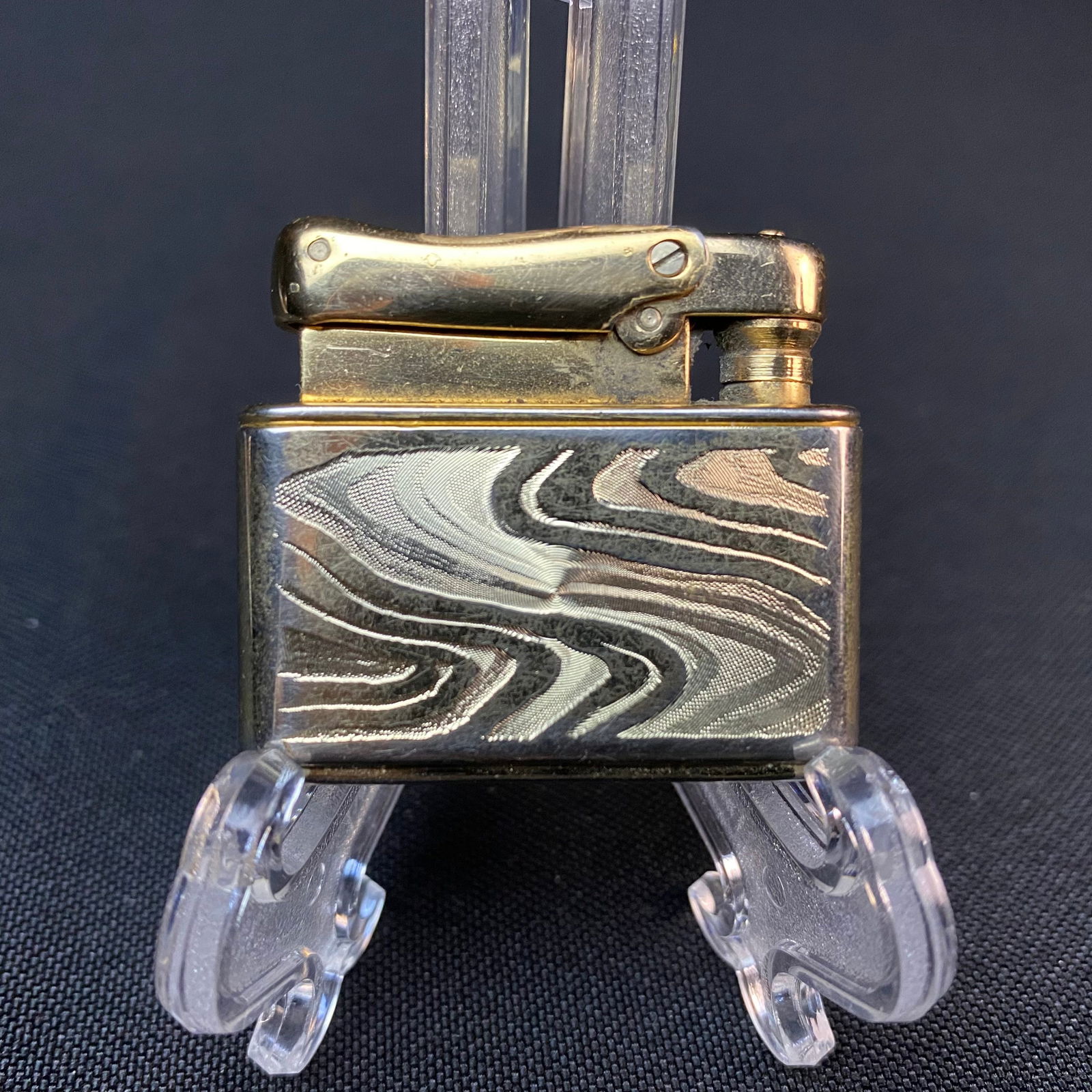 Colibri by Kreisler Gold and Silver Wave Pattern Lighter: Colibri by Kreisler Gold and Silver Wave Pattern Lighter. Used. Condition is good. Colibri by Kreisler US PAT N2671325 stamped on bottom of lighter. Lighter measures 1 9/16 tall by 1 5/8 wide by 9/16