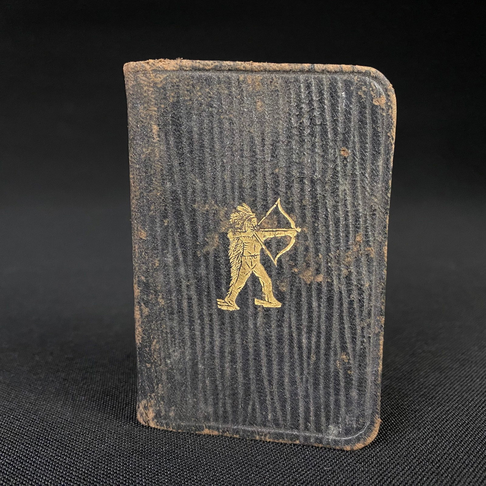 Tiny Pocket notebook with embossed gold leaf native American archer: Tiny Pocket notebook with embossed gold leaf native American archer. It is in good condition and unused, with some minor surface grime and some bowing of the front cover. It measures 3 1/8 tall by 2 1