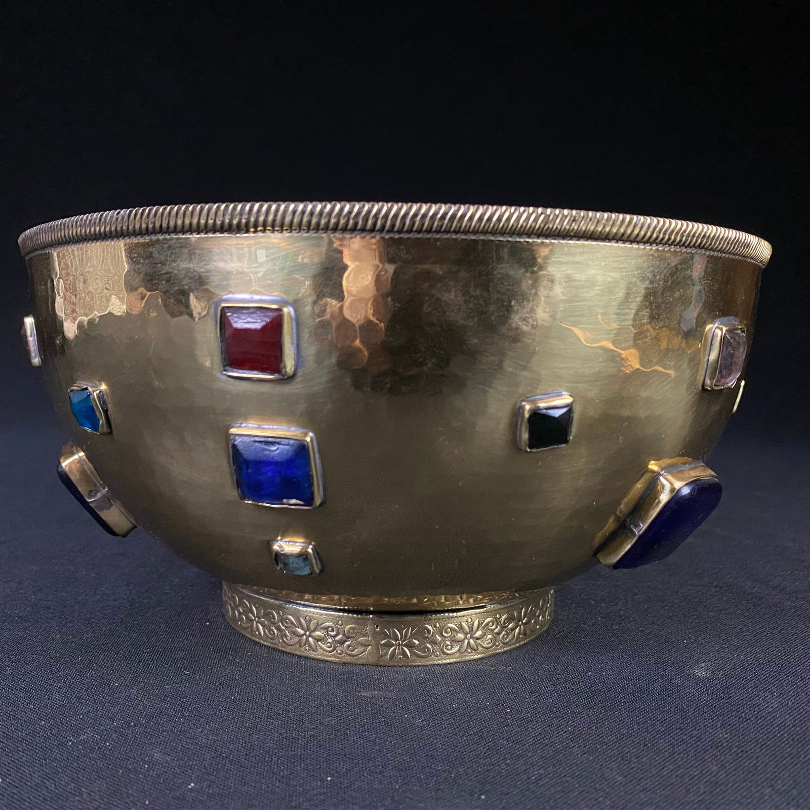 Hammered Brass Bowl with Glass Gem adornments: Hammered Brass Bowl with Glass Gem adornments. It has a slightly brass hued silver exterior, with a brighter brass hued interior, and a rope detailed brim. The Gem sets and Base were braised on. The b
