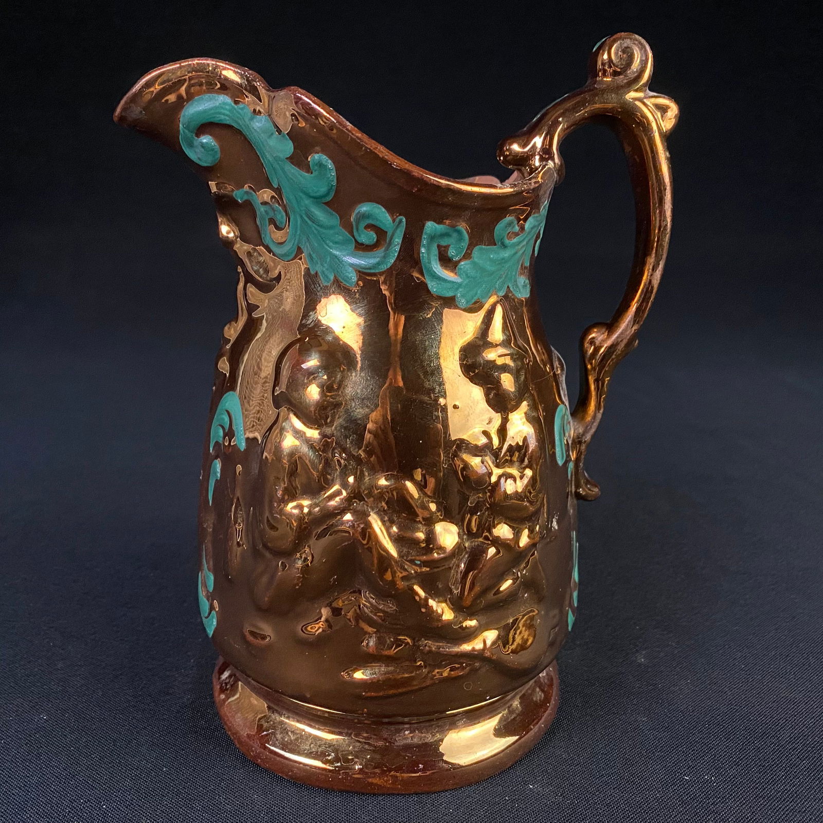 Metallic Glazed Ceramic Pitcher: Metallic Glazed Ceramic Pitcher. Condition is fair with some moderate damage. It has a chip on the brim near the handle, that radiates out with a crack that tracks through the vessel, between the hand