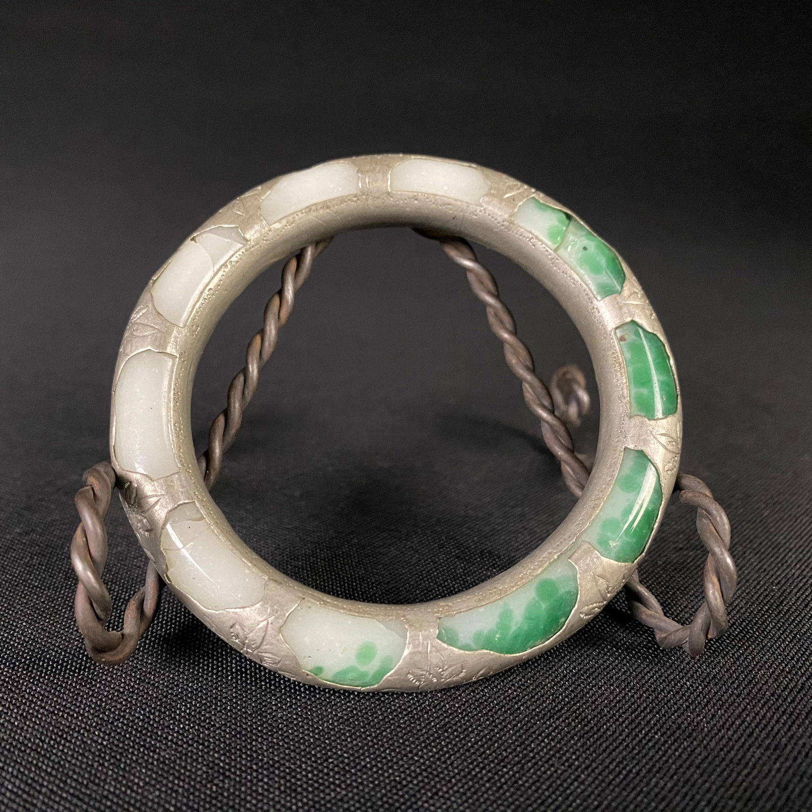 Green and White Stone Bracelet Bound in Silver: Green and White Stone Bracelet Bound in Silver. Round and cylindrical carved stone bracelet bound in silver sleeve with flower design at each node that wraps around the stone entirely. Condition is go