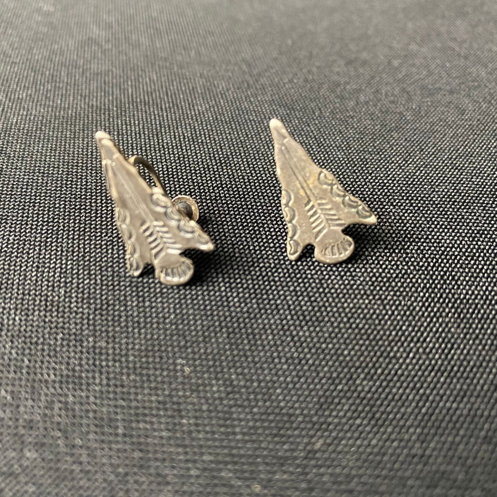 Sterling Silver Arrowhead Screw Back Earrings: Sterling Silver Arrowhead Screw Back Earrings. They are in Excellent condition with Minor surface wear and grime. They are in the shape of a flint knapped arrowhead, with stamped designs on the front,
