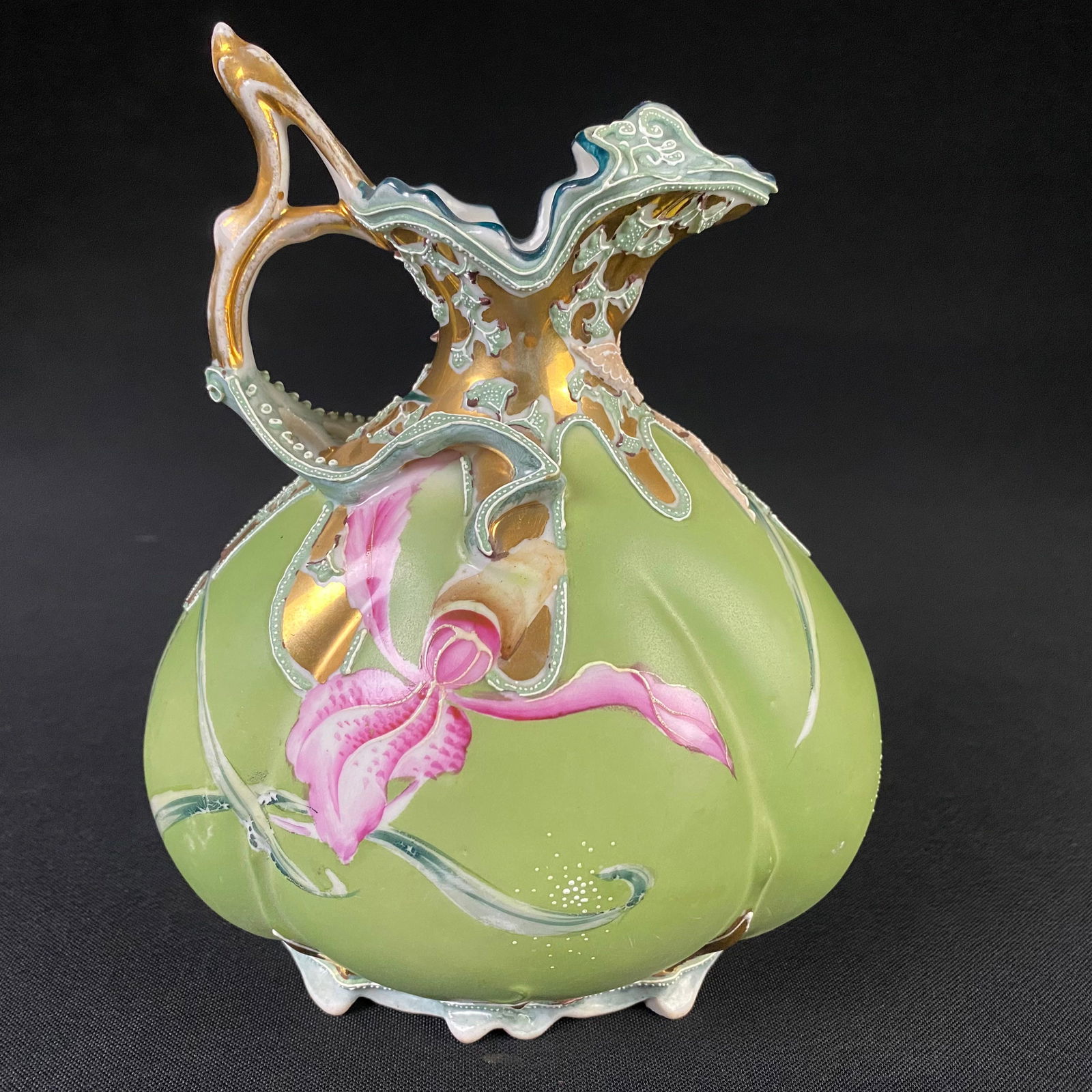 Ornate Satsuma Style Green Ceramic Pitcher with Pink Orchid Designs: Ornate Green Ceramic Pitcher with Pink Orchid Designs. In the style of Satsuma Japan. It is in excellent condition with no chips, cracks or breaks, and very minor surface wear and grime. It has multip