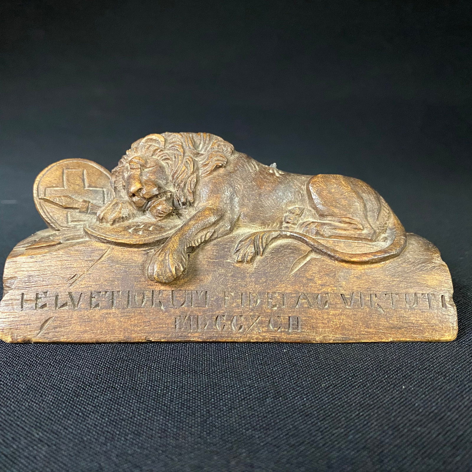 Carved Wooden Lion of Lucerne with Latin Writing: Carved Wooden Lion of Lucerne with Latin Writing. It is in great condition with little damage and surface wear. The spear that protrudes from the lion's back is broken off, and there is a bit of heavi