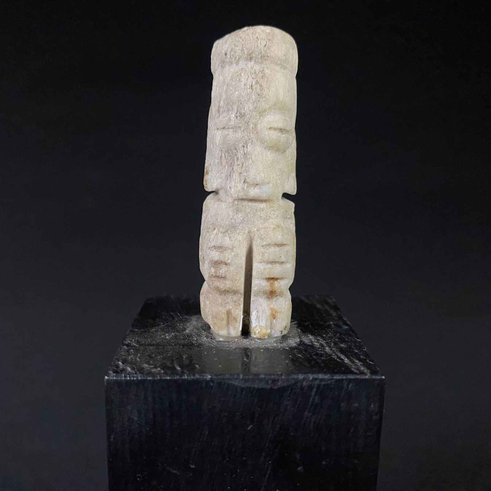 Ancient Pre Columbian Hand Carved Stone Statue Mounted on Wood Plinth: Small Ancient Pre-Columbian Hand Carved Stone Statue Mounted on a Tall Block of Pitch Black Wood. It is in great condition with no chips, cracks, or breaks, and minor surface wear to the pedestal and