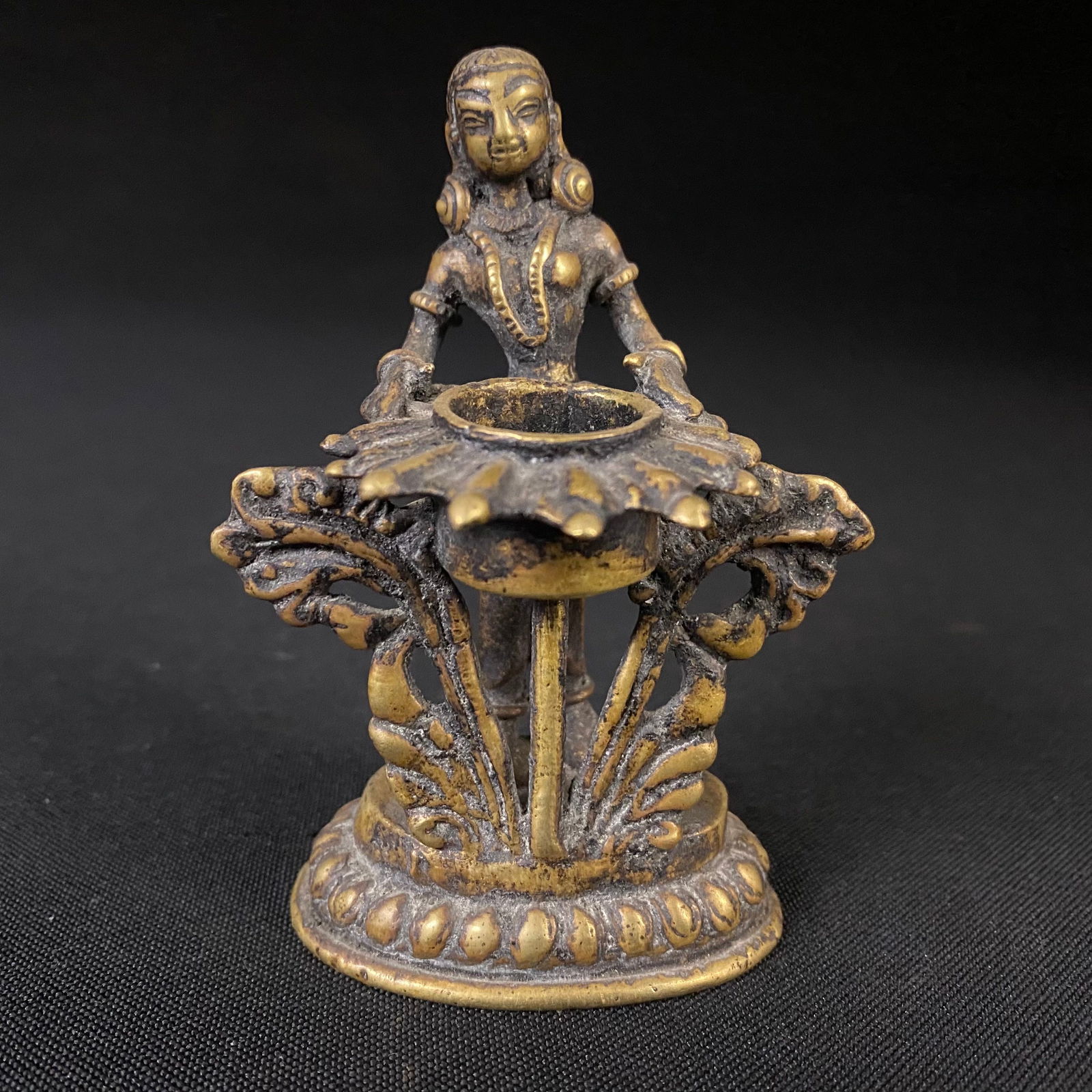 Antique Cast Bronze Deepalakshmi Lakshmi Figurine with a Floral and Foliate Pedestal Vessel: Antique Cast Brass Deepalakshmi Lakshmi Figurine with a Floral and Foliate Pedestal Candle Holder. An auspicious element in Hindu tradition, Deepalakhsmi is a representation of Goddess Lakshmi, holdin