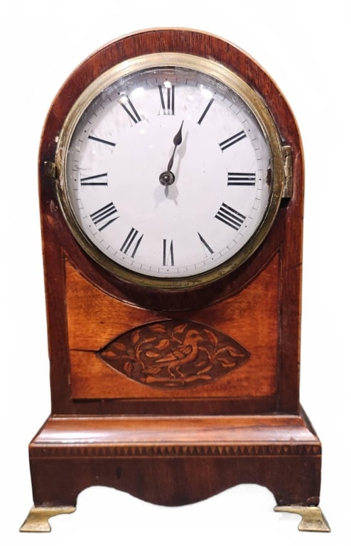 INLAID MAHOGANY CASE MANTEL CLOCK W/BRASS FEET: MAHOGANY CASED MANTEL CLOCK WITH BRASS FEET, ROMAN NUMERAL DIAL, AND CARVED WOODEN PANEL. FEATURES A BRASS MECHANICAL MOVEMENT VISIBLE FROM THE REAR. 10-1/2" x 6-1/2" x 3-1/2"