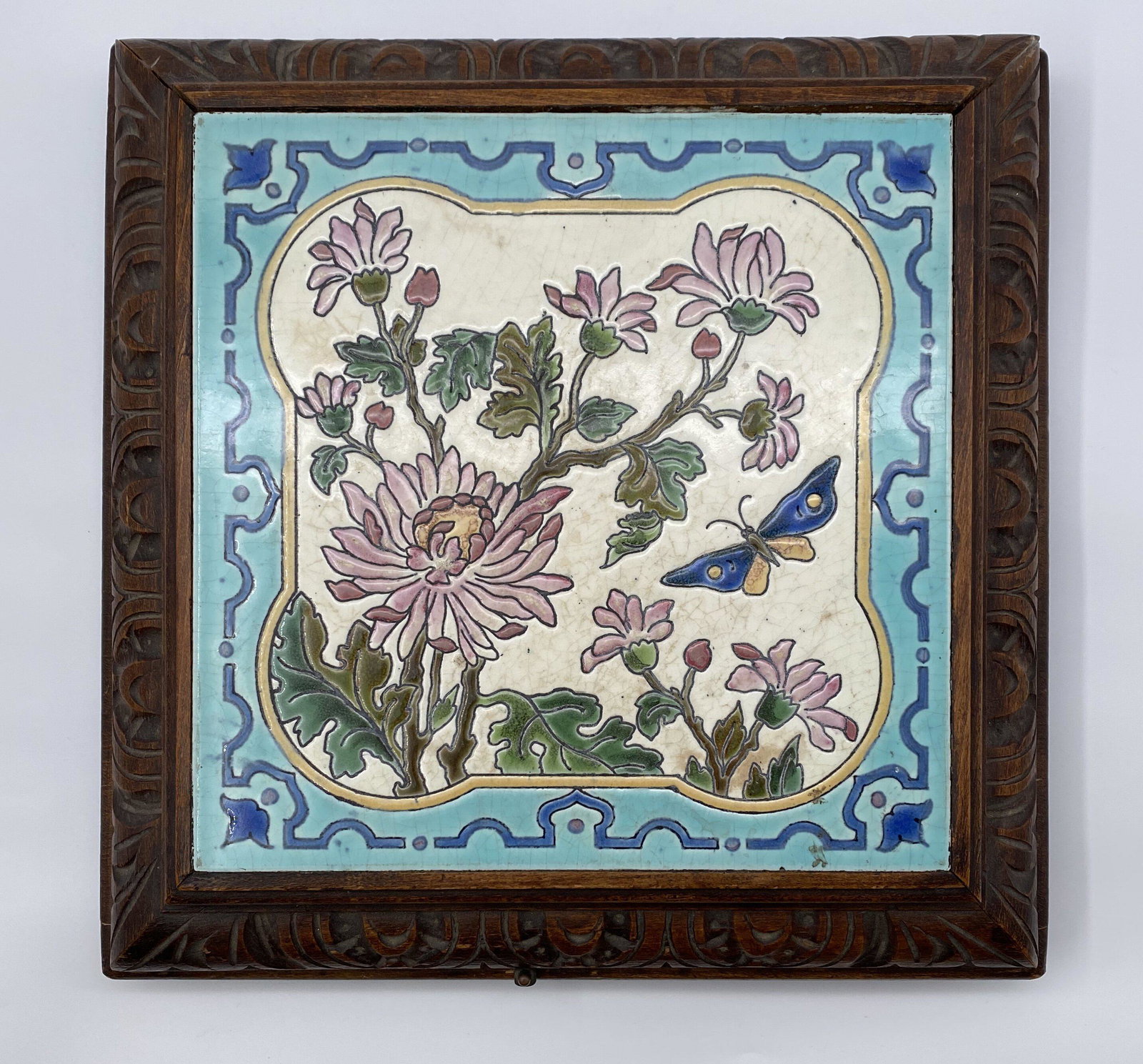 Floral and butterfly Longwy tile set as a musical table: This beautiful Longwy tile features a floral scene with a butterfly that is encased in an ornately carved wooden frame. This ingenious piece is also a music box! There is a key on the underside to win