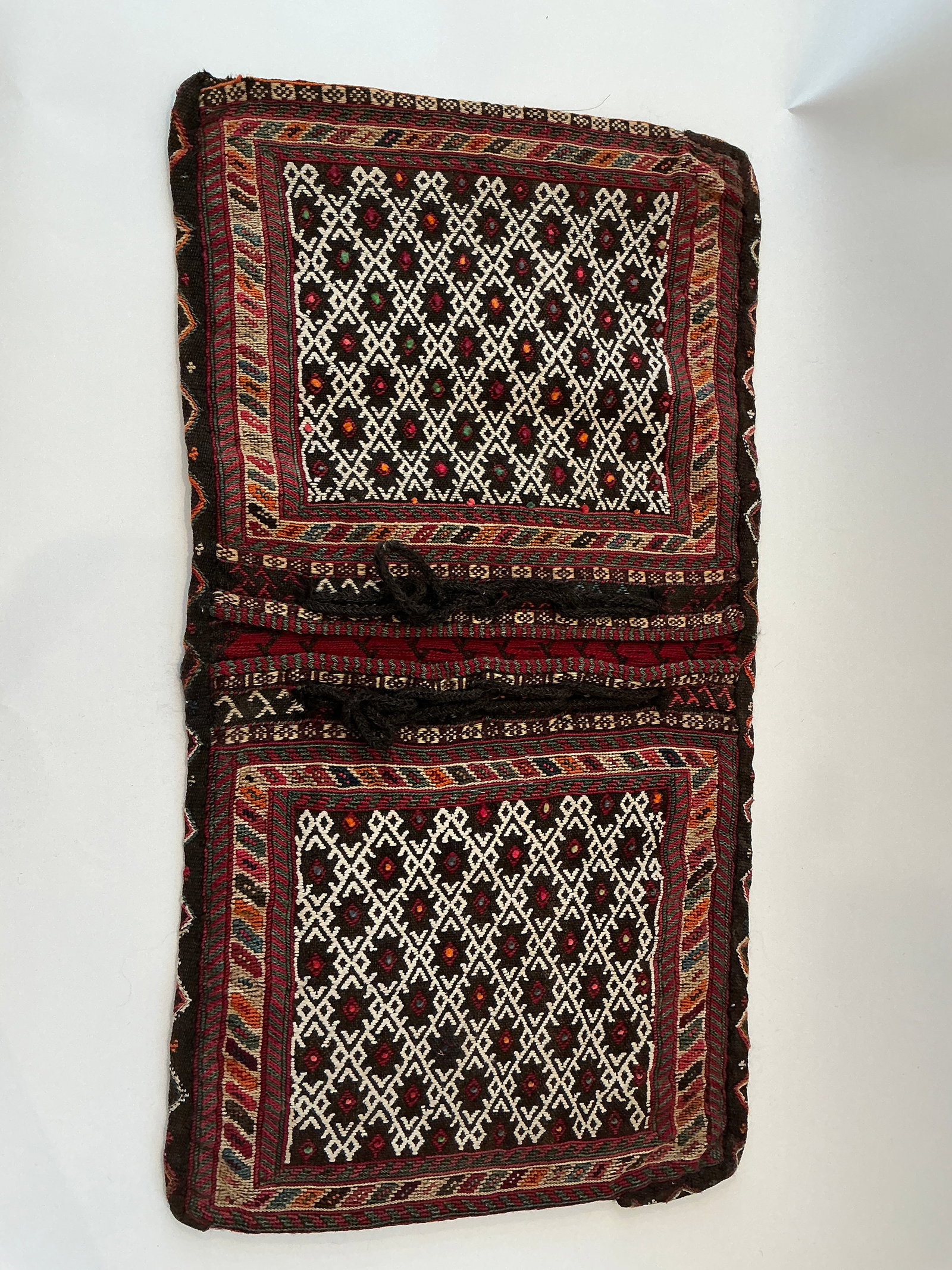 Vintage Tribal Camel Saddle Rug with Geometric Patterns: This vintage tribal camel saddle rug features intricate geometric patterns, showcasing the traditional artisanship of West African design. The vibrant palette includes rich reds, bright whites, and ea