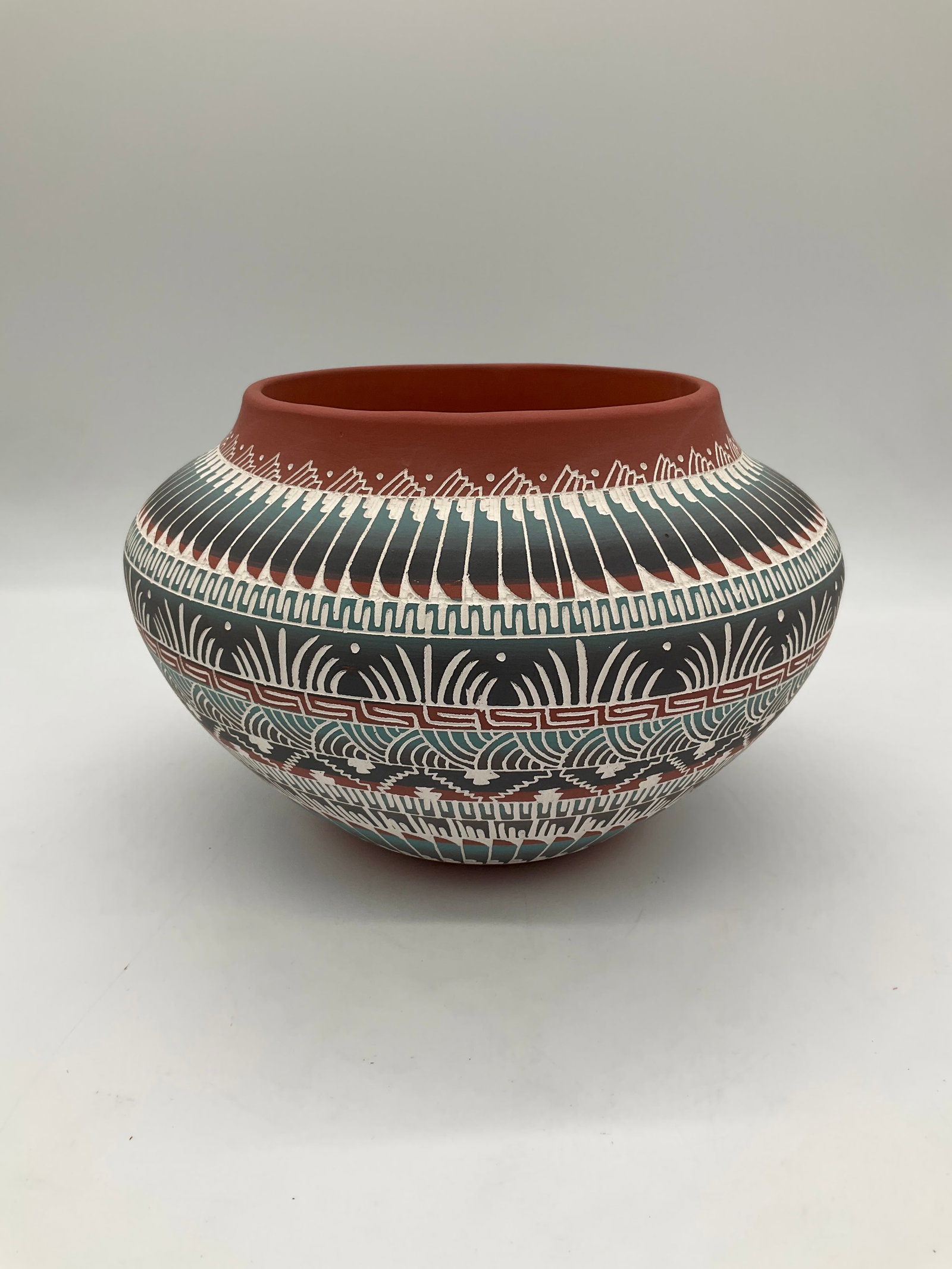 V. King Navajo Pottery Bowl – Southwestern Design: This striking pottery bowl by H. King showcases a vibrant Southwestern or Indigenous-inspired design, featuring hand-painted geometric and linear patterns in red, white, and blue-gray hues. The exteri