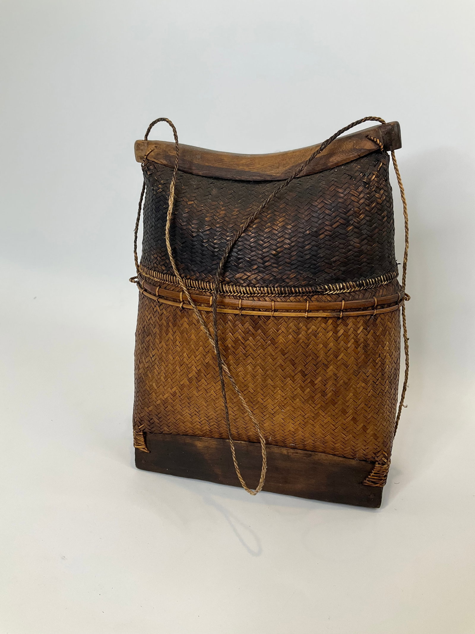 Vintage Woven Basket Bag with Wooden Accents: This unique decor item is a woven basket bag, showcasing intricate craftsmanship with natural fibers. Its rectangular shape features a two-toned color scheme, with a darker upper portion transitioning