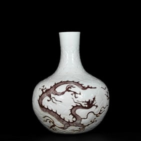 A UNDERGLAZED RED CARVED 'DRAGON IN WAVES' GLOBULAR VASE