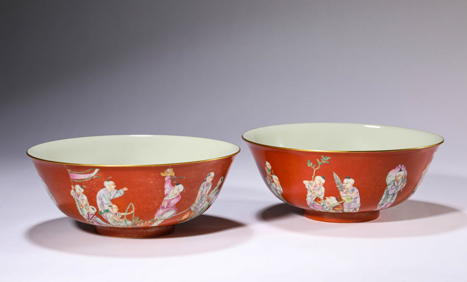 A PAIR OF CORAL-RED GROUND FAMILLE-ROSE 'CHILDREN AT PLAY' BOWLS: A PAIR OF CORAL-RED GROUND FAMILLE-ROSE 'CHILDREN AT PLAY' BOWLS Dimensions: Width: 19.7 cm (7.76 in) x Height: 7.8 cm (3.07 in). All measurements are approximate.