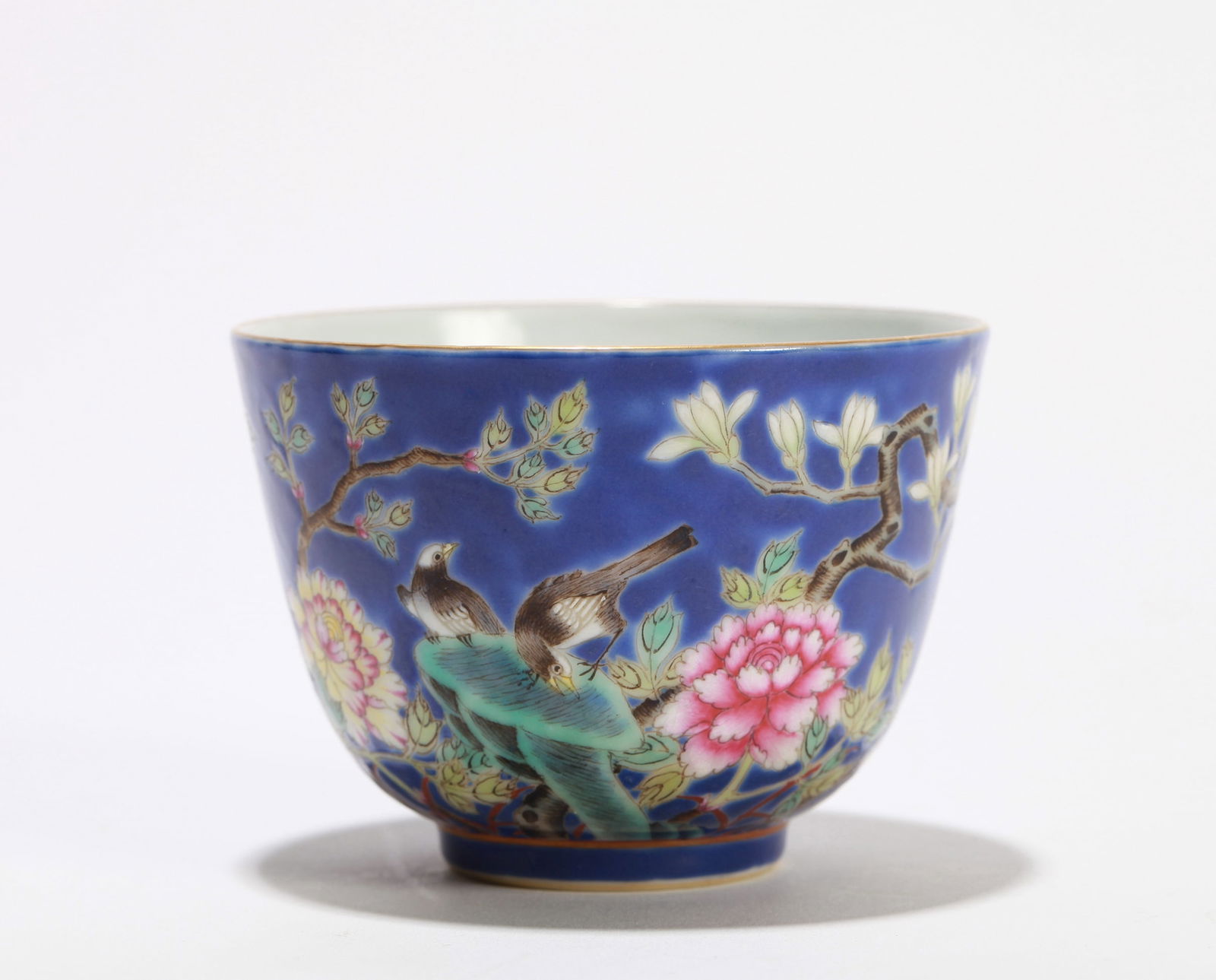 A BLUE-GROUND FAMILLE ROSE 'FLOWERS AND BIRDS' CUP: A BLUE-GROUND FAMILLE ROSE 'FLOWERS AND BIRDS' CUP Diameter: 8.5 cm (3.35 in.) x Height: 6.5 cm (2.56 in.). All measurements are approximate.