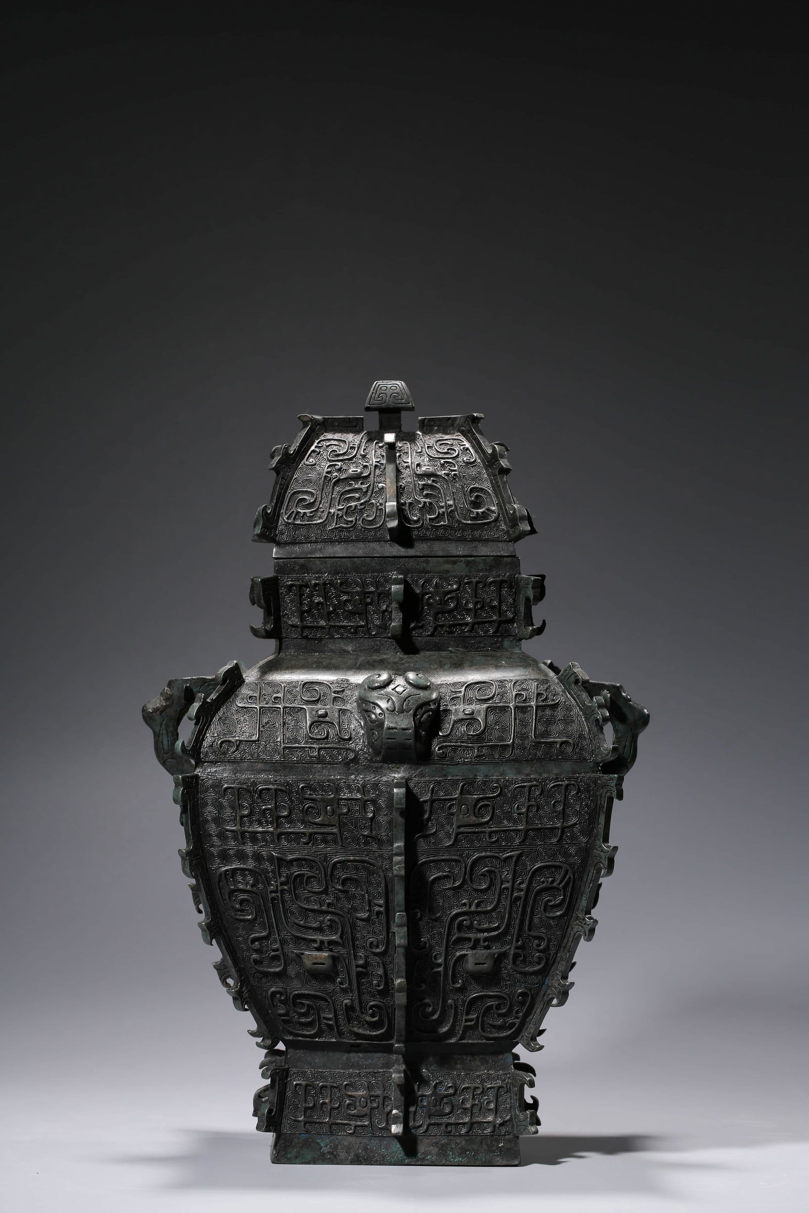 A BRONZE 'ARCHAISTIC' 'FLANGED SQUARE YI' RITUAL VESSEL: A BRONZE 'ARCHAISTIC' 'FLANGED SQUARE YI' RITUAL VESSEL Dimensions: Weight: 7.8kg. Length: 29.8 cm (11.73 in) x Width: 23.6 cm (9.29 in) x Height: 45.4 cm (17.87 in). All measurements are approximate.