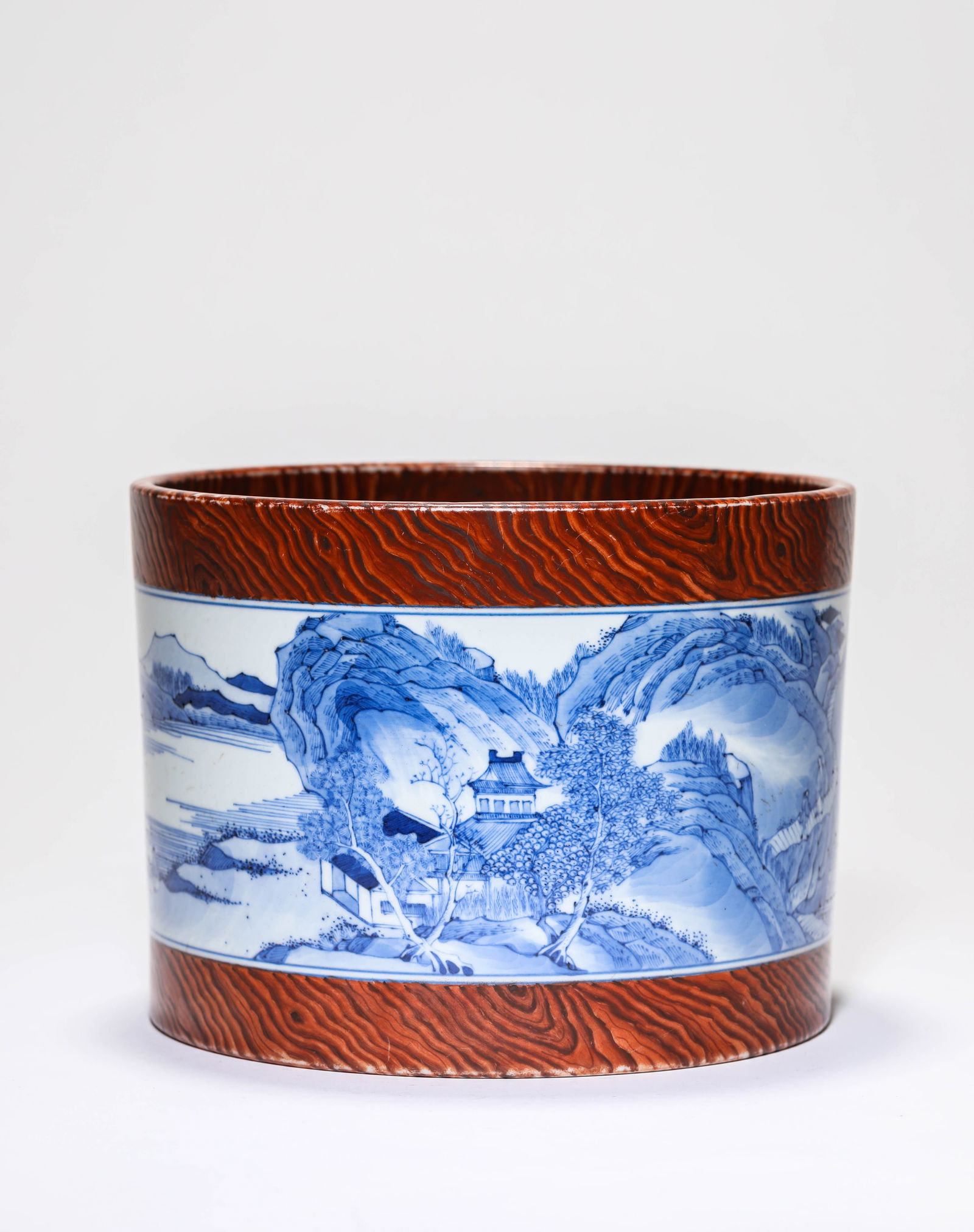 A 'WOOD-GRAIN-GLAZED' BLUE AND WHITE 'LANDSCAPE AND FIGURES' BRUSH POT: A 'WOOD-GRAIN-GLAZED' BLUE AND WHITE 'LANDSCAPE AND FIGURES' BRUSH POT Dimensions: Width: 18.2 cm (7.17 in) x Height: 13.8 cm (5.43 in). All measurements are approximate.