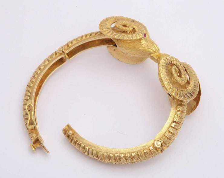 GOLD DOUBLE SHEEP HEAD BRACELET, SET WITH TWO FACETED RUBIES AND TWO FACETED SAPPHIRES: GOLD DOUBLE SHEEP HEAD BRACELET, SET WITH TWO FACETED RUBIES AND TWO FACETED SAPPHIRESDescription:This 18K gold double sheephead bracelet is set with two faceted rubies and two faceted sapphires. The