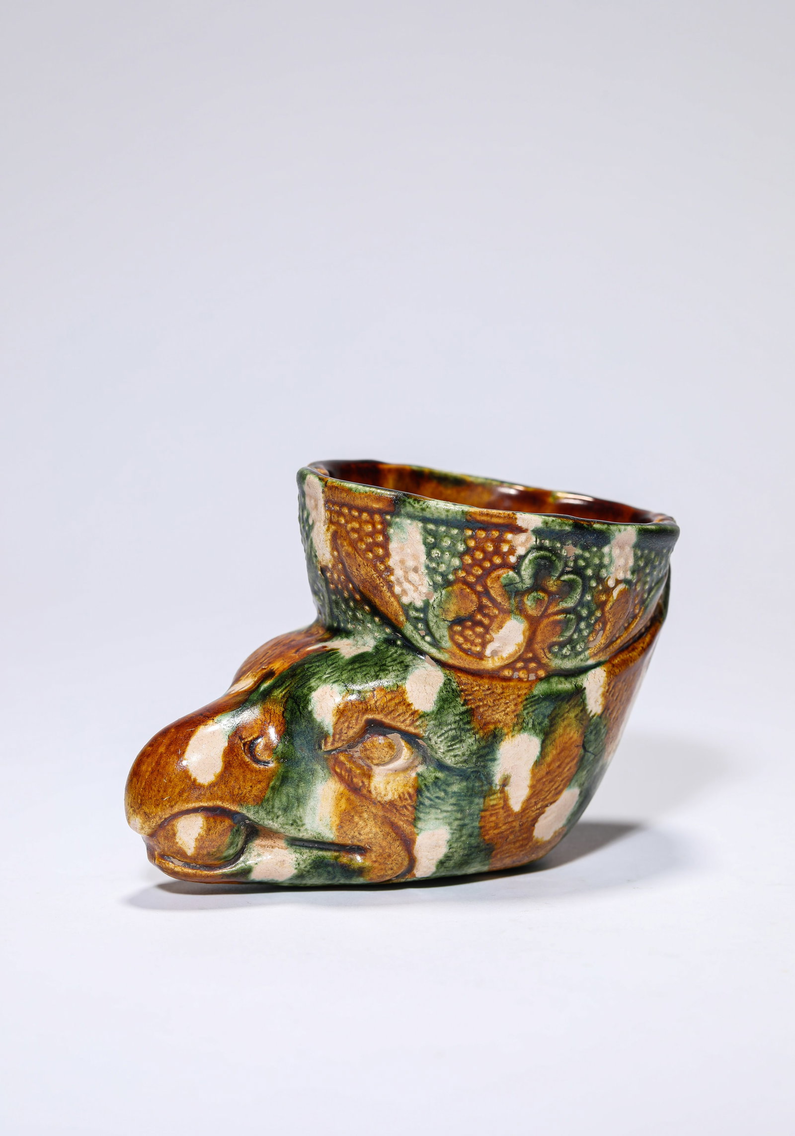 A SANCAI-GLAZED CUP: A SANCAI-GLAZED CUP Dimensions: Length: 10.5 cm (4.13 in) x Width: 6.8 cm (2.68 in) x Height: 7.8 cm (3.07 in). All measurements are approximate.
