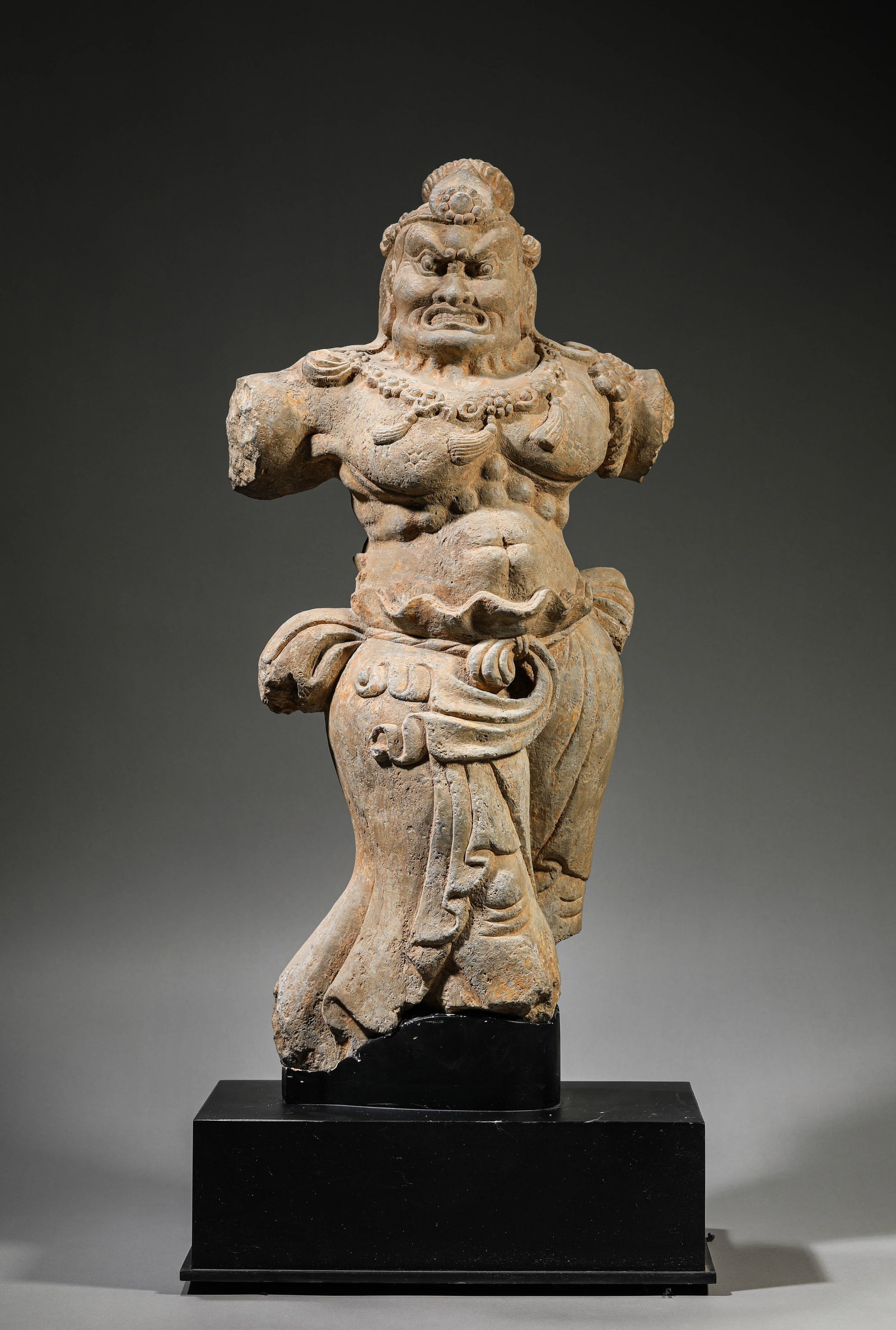 A STONE FIGURE OF A GUARDIAN: A STONE FIGURE OF A GUARDIAN Dimensions: Weight: 30kg. Length: 33.0 cm (12.99 in) x Width: 23.0 cm (9.06 in) x Height: 73.0 cm (28.74 in). All measurements are approximate.