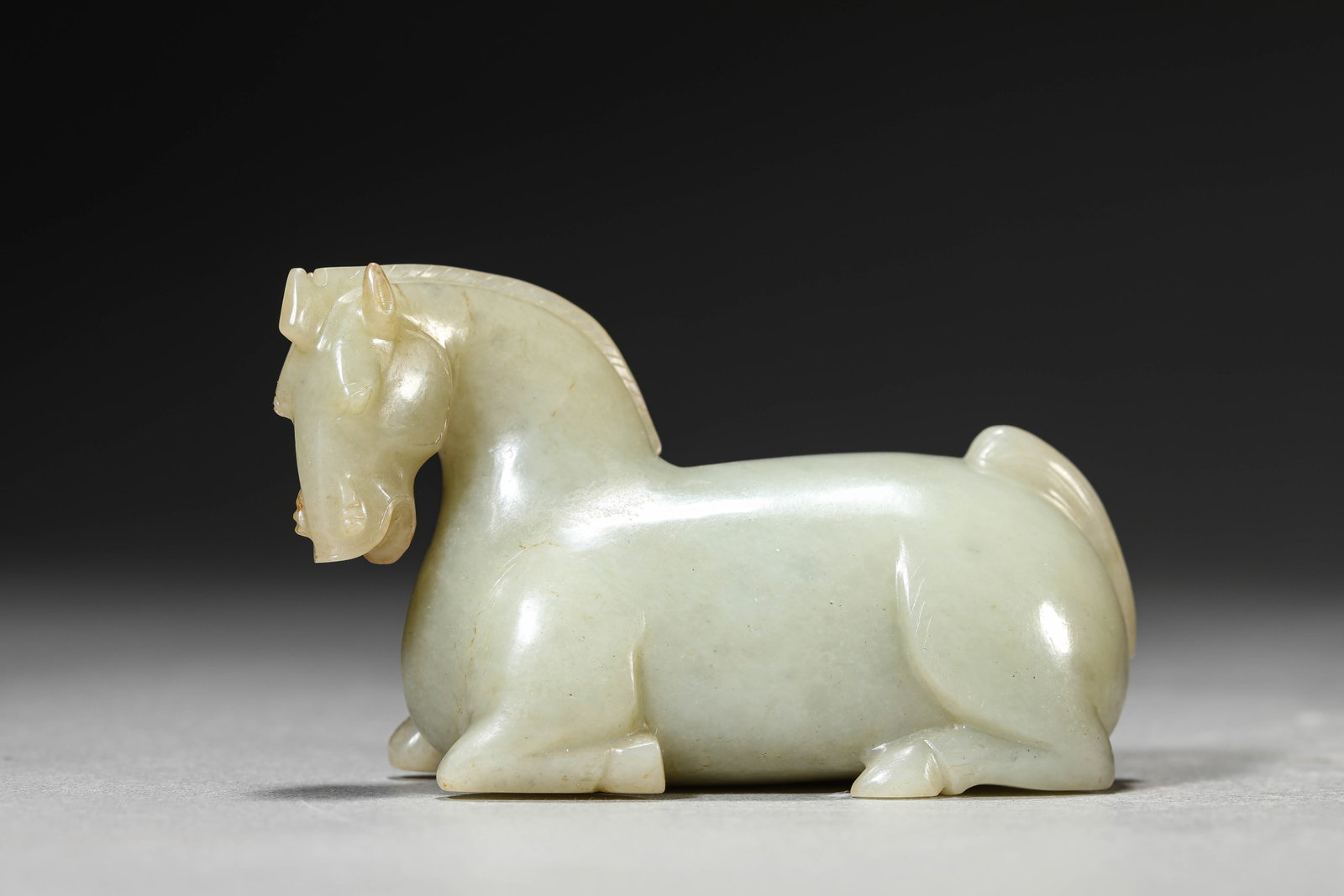 A JADE RECUMBENT HORSE: A JADE RECUMBENT HORSE Dimensions: Length: 11.0 cm (4.33 in) x Width: 4.5 cm (1.77 in) x Height: 6.5 cm (2.56 in). All measurements are approximate.