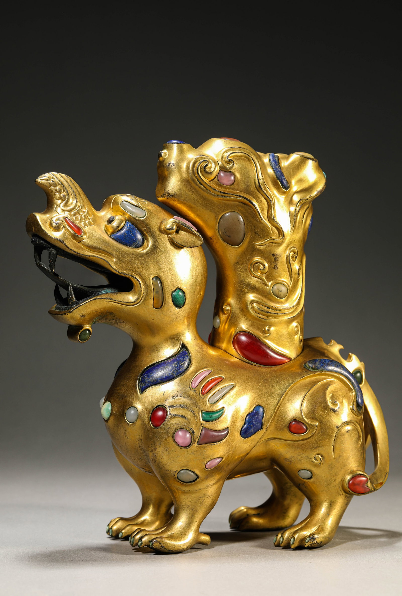 A GILT-BRONZE AND GEM-INLAID 'AUSPICIOUS BEAST': A GILT-BRONZE AND GEM-INLAID 'AUSPICIOUS BEAST' Dimensions: Weight: 5720g. Length: 25.0 cm (9.84 in) x Width: 10.2 cm (4.02 in) x Height: 26.5 cm (10.43 in). All measurements are approximate.