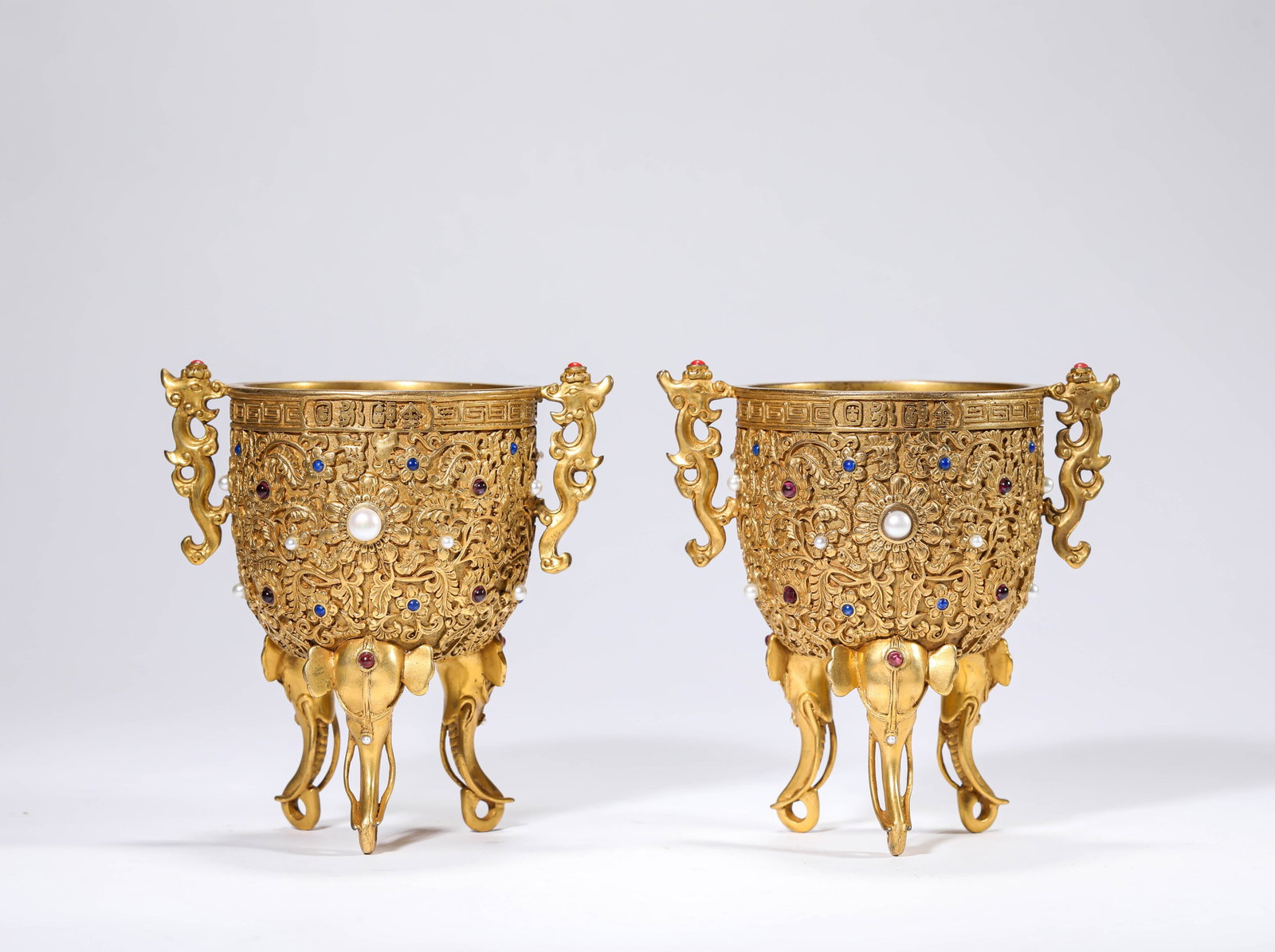 A PAIR OF GILT-BRONZE AND 'HUNDRED TREASURES' -INLAID CUPS: A PAIR OF GILT-BRONZE AND 'HUNDRED TREASURES' -INLAID CUPS Dimensions: Weight: 785g. Length: 11.2 cm (4.41 in) x Width: 9.5 cm (3.74 in) x Height: 10.8 cm (4.25 in). All measurements are approximate.