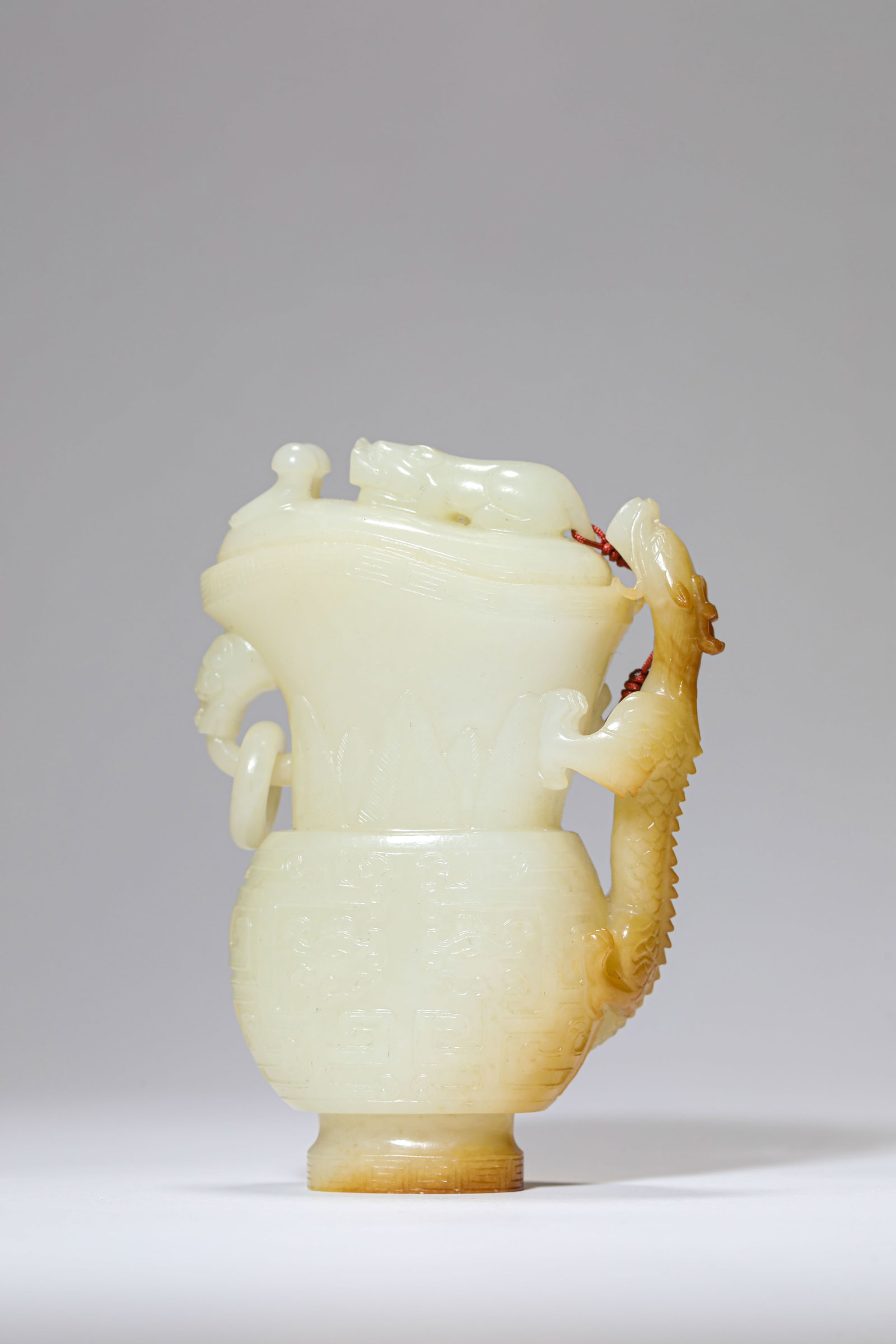 A JADE 'ANIMAL MASK AND DRAGON' 'GONG-FORM' CUP: A JADE 'ANIMAL MASK AND DRAGON' 'GONG-FORM' CUP Dimensions: Length: 8.5 cm (3.35 in) x Width: 3.8 cm (1.50 in) x Height: 11.9 cm (4.69 in). All measurements are approximate.