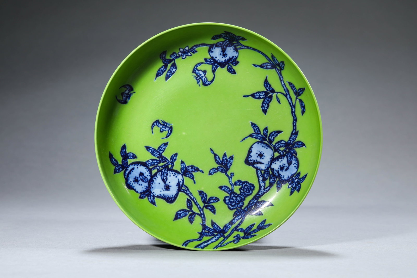 A GREEN-GLAZED AND BLUE AND WHITE 'BAT AND SHOU' DISH: A GREEN-GLAZED AND BLUE AND WHITE 'BAT AND SHOU' DISH Dimensions: Width: 19.8 cm (7.80 in) x Height: 4.1 cm (1.61 in). All measurements are approximate.