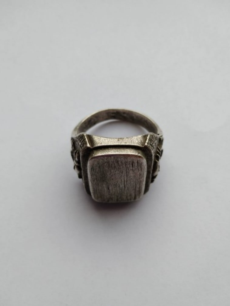 SOLID METAL RING: SOLID METAL RING Description: A solid metal ring with a dark oval inset or raised central element. The piece should be reviewed for ring size, metal marks, surface oxidation, scratches, setting condit
