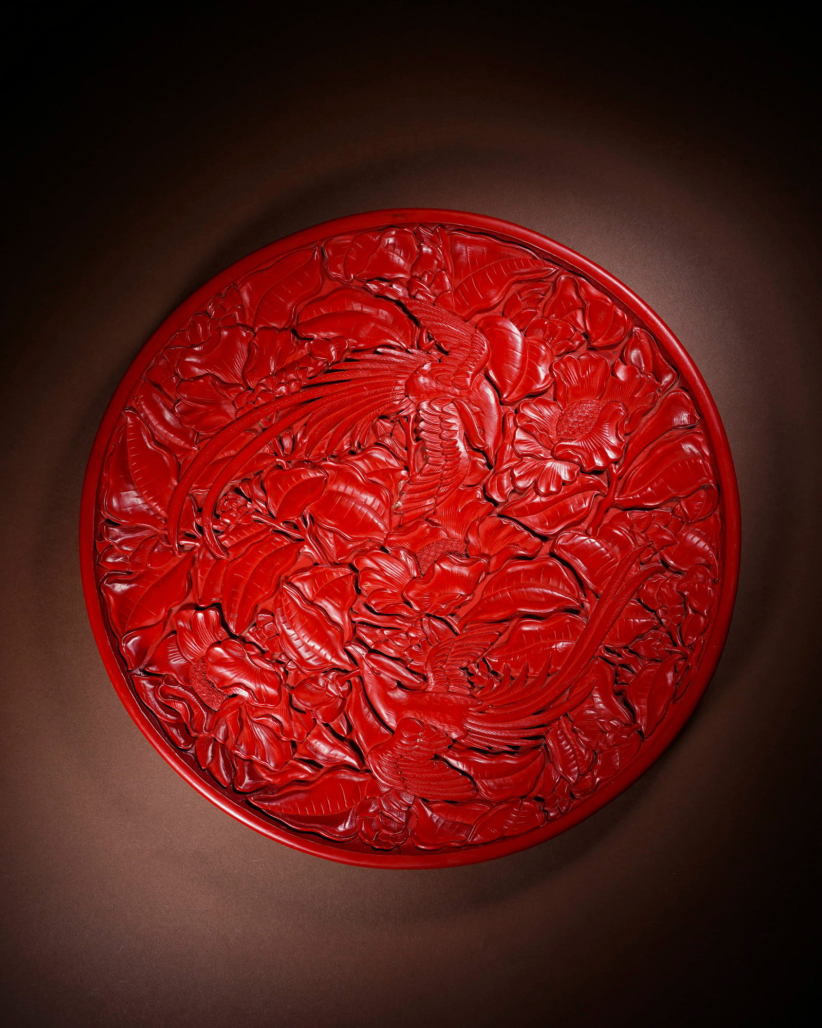 A CARVED CINNABAR LACQUER 'PHOENIX AND PEONY' DISH: A CARVED CINNABAR LACQUER 'PHOENIX AND PEONY' DISH Dimensions: Length: 34.7 cm (13.66 in.), Width: 34.7 cm (13.66 in.). All measurements are approximate.