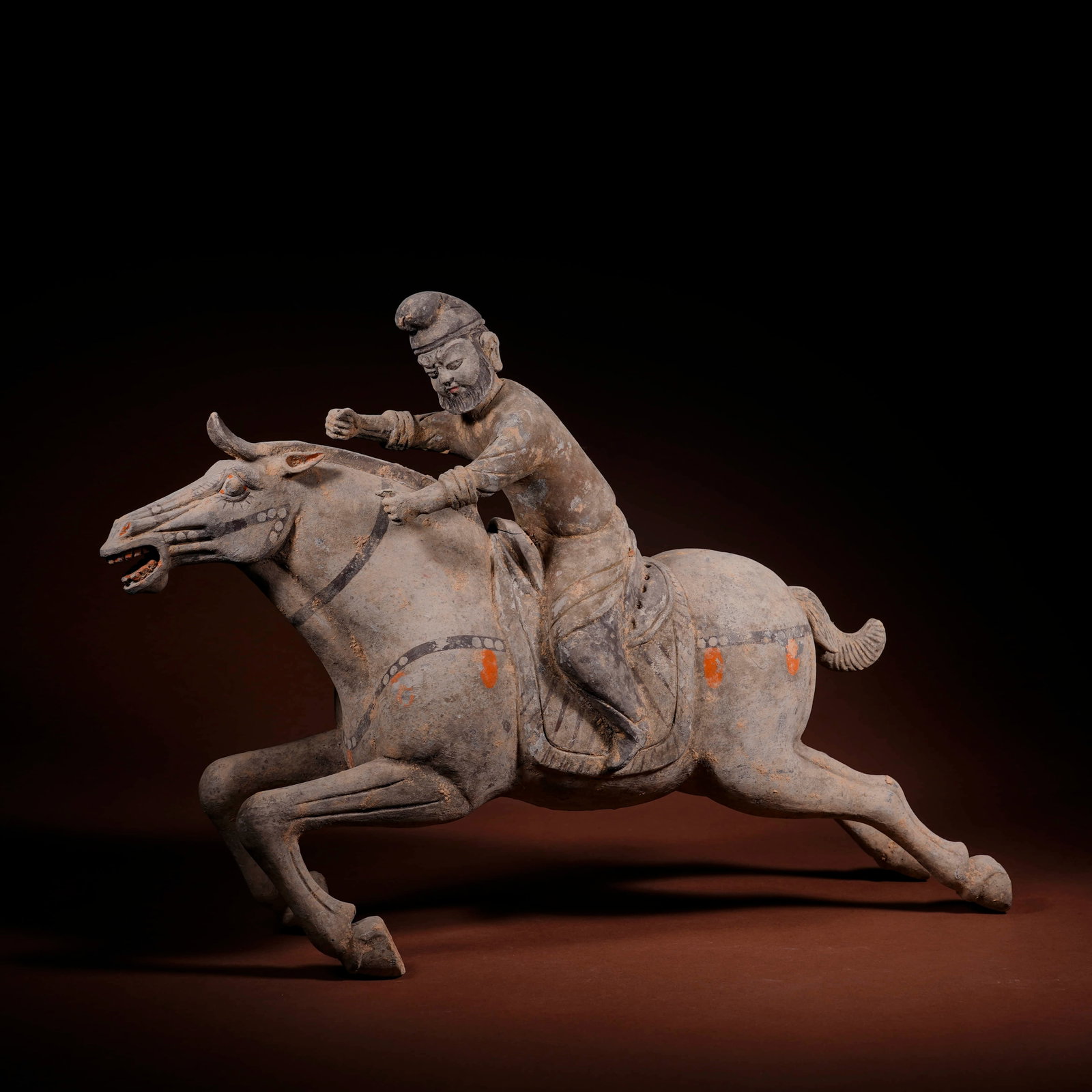 A PAINTED POTTERY 'POLO-PLAYER' FIGURINE: A PAINTED POTTERY 'POLO-PLAYER' FIGURINE Dimensions: Length: 40 cm (15.75 in.), Height: 28.5 cm (11.22 in.). All measurements are approximate.