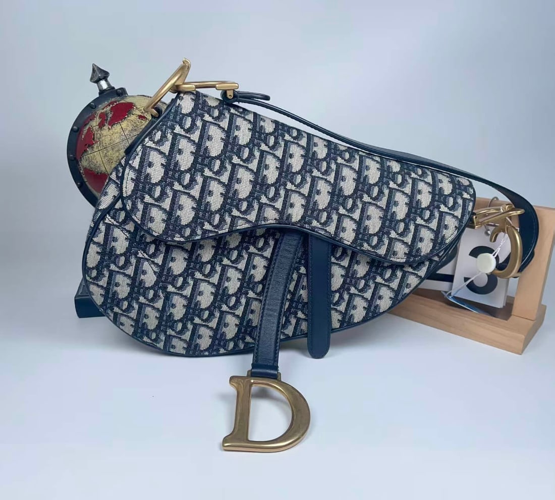 DIOR SADDLE OBLIQUE SHOULDER BAG: DIOR SADDLE OBLIQUE SHOULDER BAG Dior Saddle Bag. Crafted from classic Oblique jacquard canvas with vintage-finish metal hardware. Designed in the house's iconic saddle-shaped silhouette, accented wit