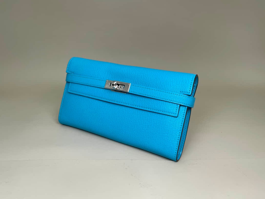 HERMÈS KELLY LONG WALLET: HERMÈS KELLY LONG WALLET Hermès Kelly Long Wallet with Matching Evelyne Strap. Crafted from blue leather in an Izmir Blue/Tanzania Blue colourway and finished with palladium-plated hardware.