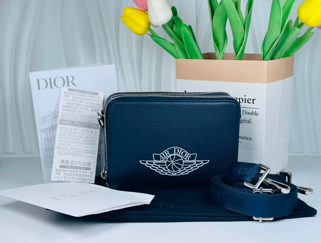 DIOR X AIR JORDAN AIR DIOR CAMERA BAG: DIOR X AIR JORDAN AIR DIOR CAMERA BAG DIOR x AIR JORDAN, Air Dior. A limited-edition camera bag crafted from navy blue grained calfskin, applied with the Air Jordan Wings emblem. Accompanied by the