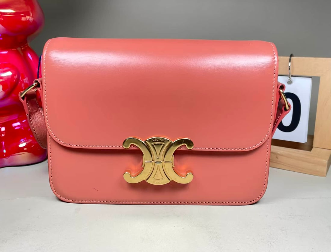 CELINE TRIOMPHE CALFSKIN TOP-HANDLE AND CROSSBODY BAG: CELINE TRIOMPHE CALFSKIN TOP-HANDLE AND CROSSBODY BAG CELINE, Triomphe. A Canyon Red calfskin bag with a metal Triomphe clasp and adjustable shoulder strap, designed for hand, shoulder or crossbody ca